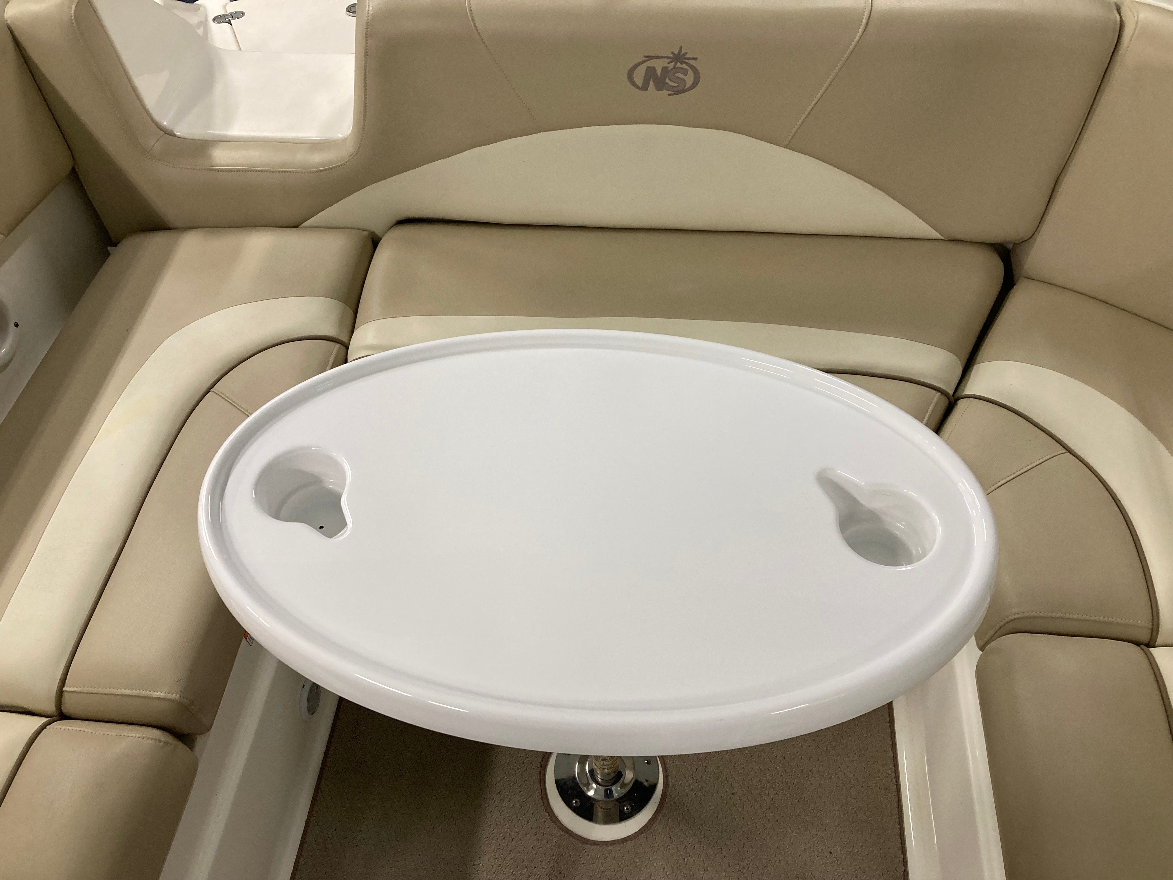 Interior view of a boat with beige cushioned seating and an oval table.