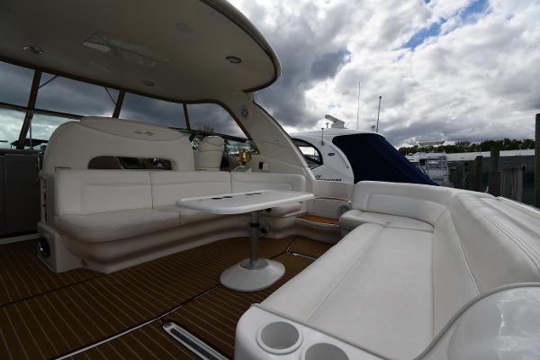 2003 Sea Ray 460 Sundancer yacht interior with white seating and table under cloudy sky.