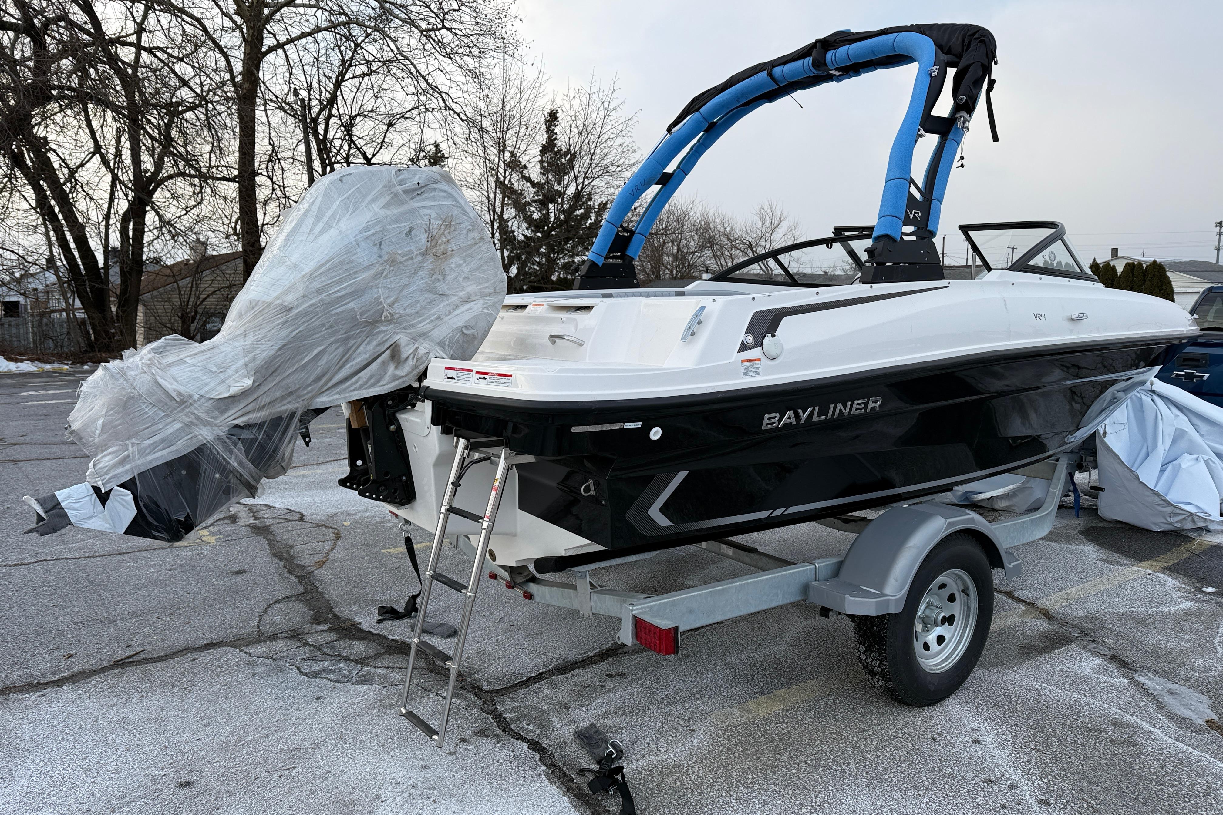 2026 Bayliner VR4 Bowrider OB on trailer, wrapped for protection, in parking lot.