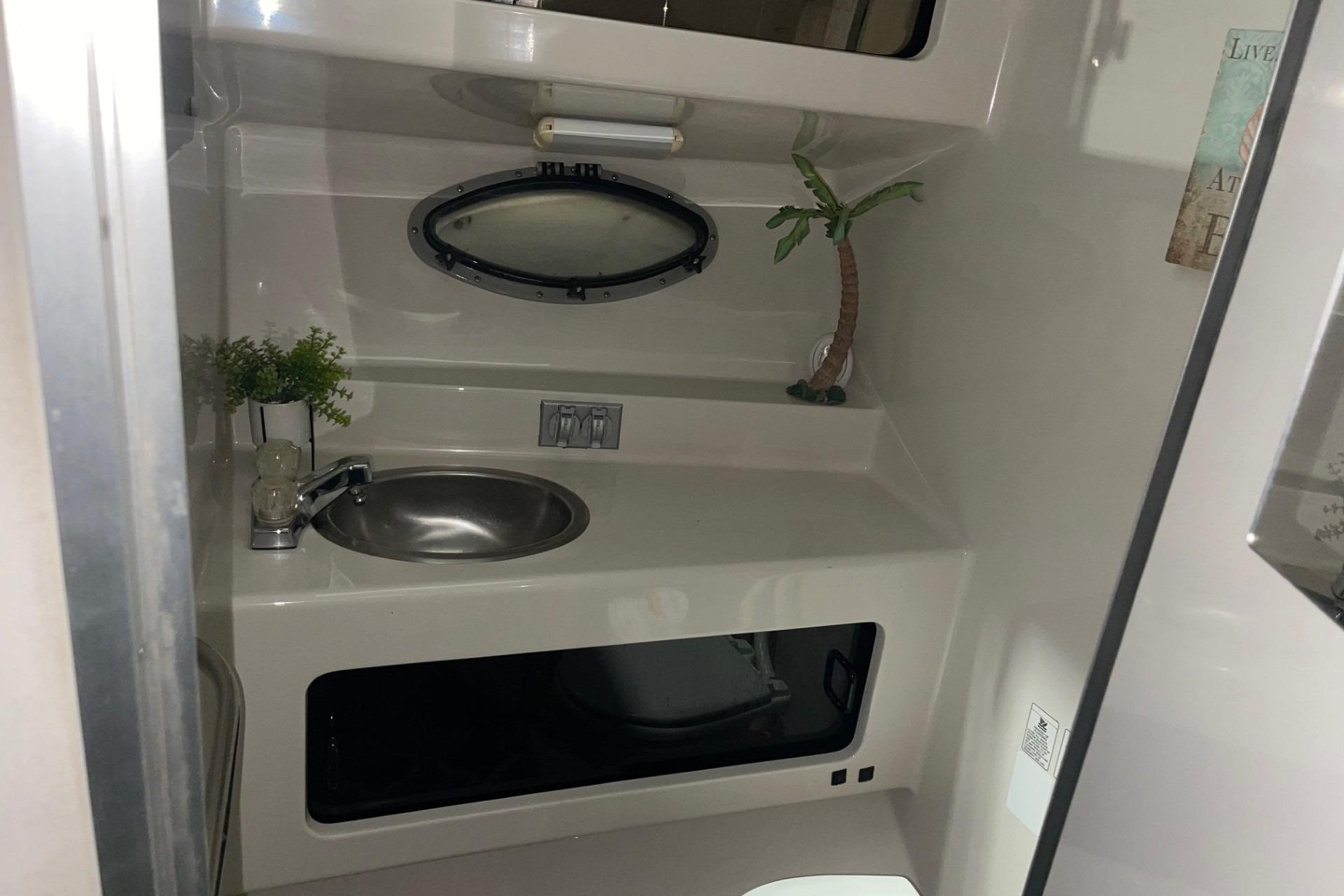 1992 Chaparral Signature 30 boat bathroom with sink, porthole, and decorative plants.