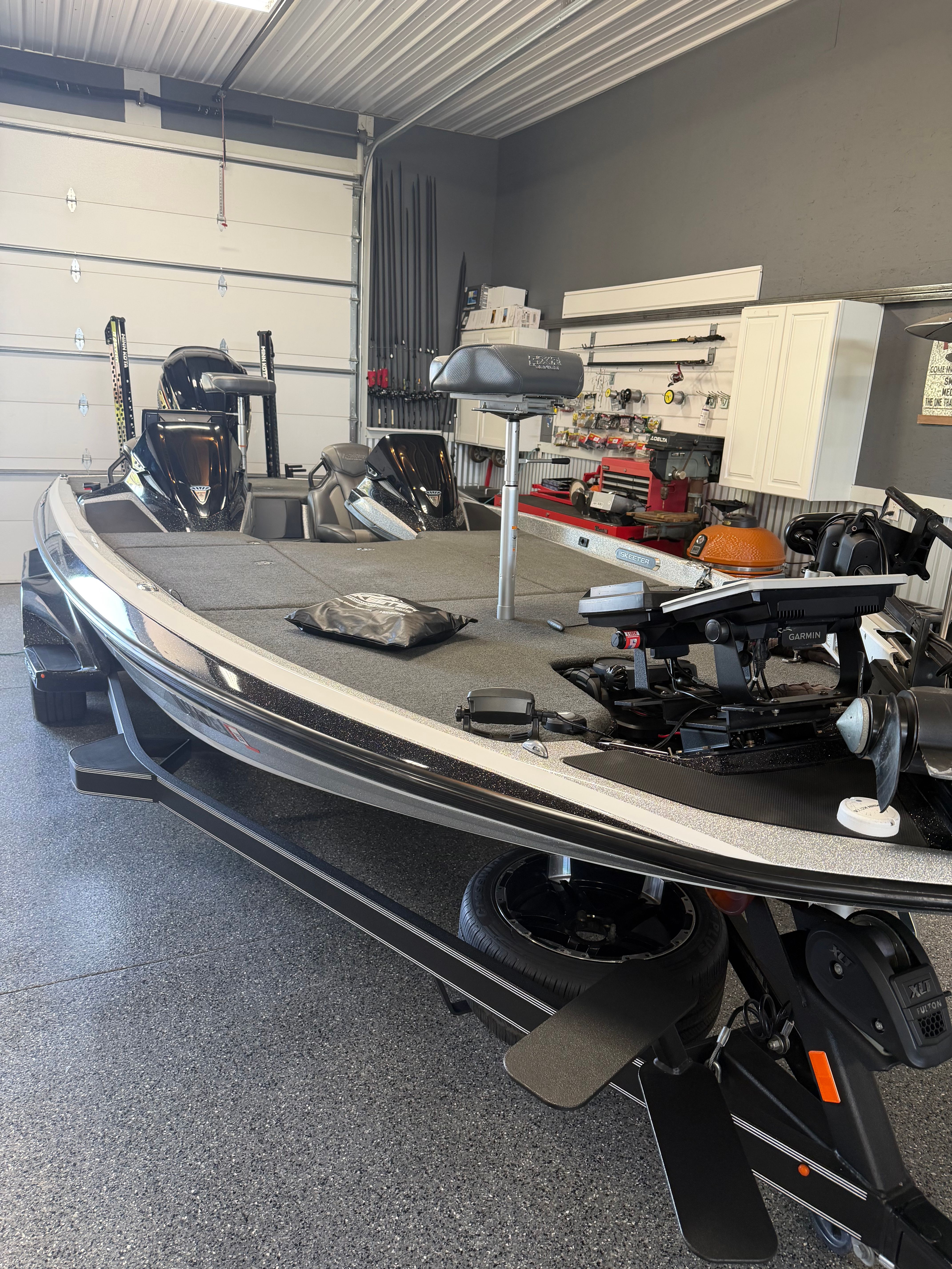 A Skeeter FXR21 Limited boat in a garage, surrounded by fishing gear.