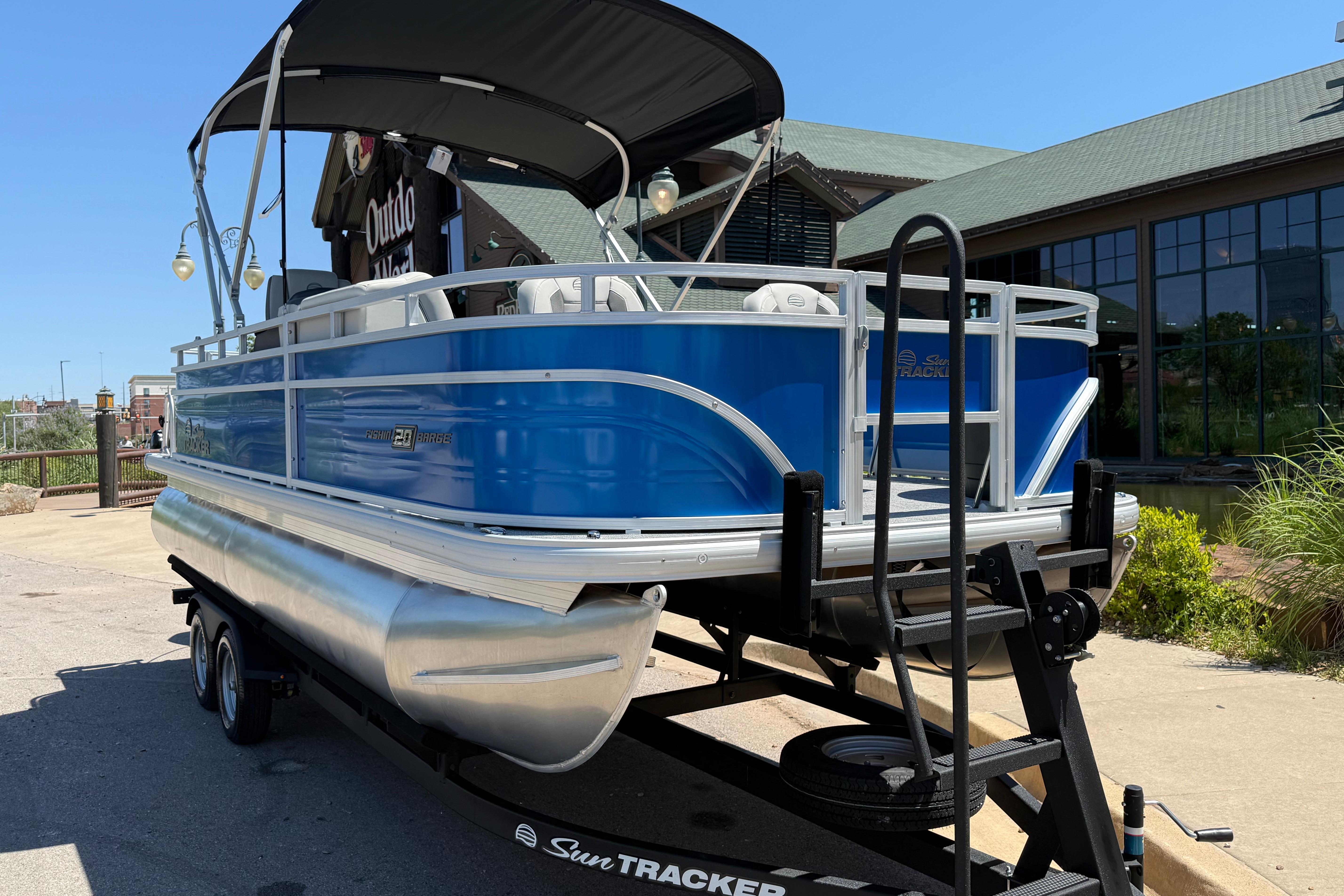2026 Sun Tracker Fishin' Barge 20 DLX pontoon boat on trailer, outdoor setting.