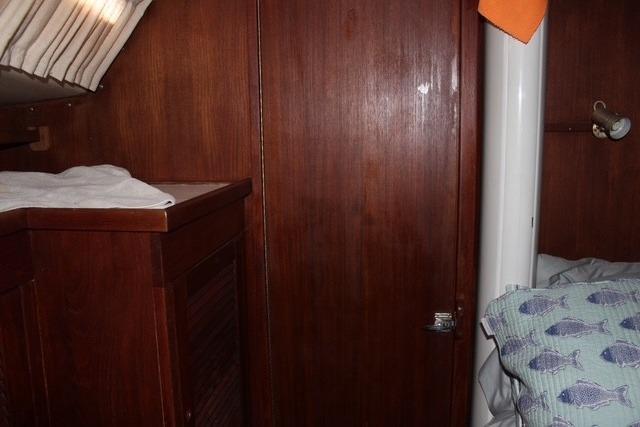Interior of 1989 Catalina 42 sailboat with wooden cabinetry and cozy bedding.