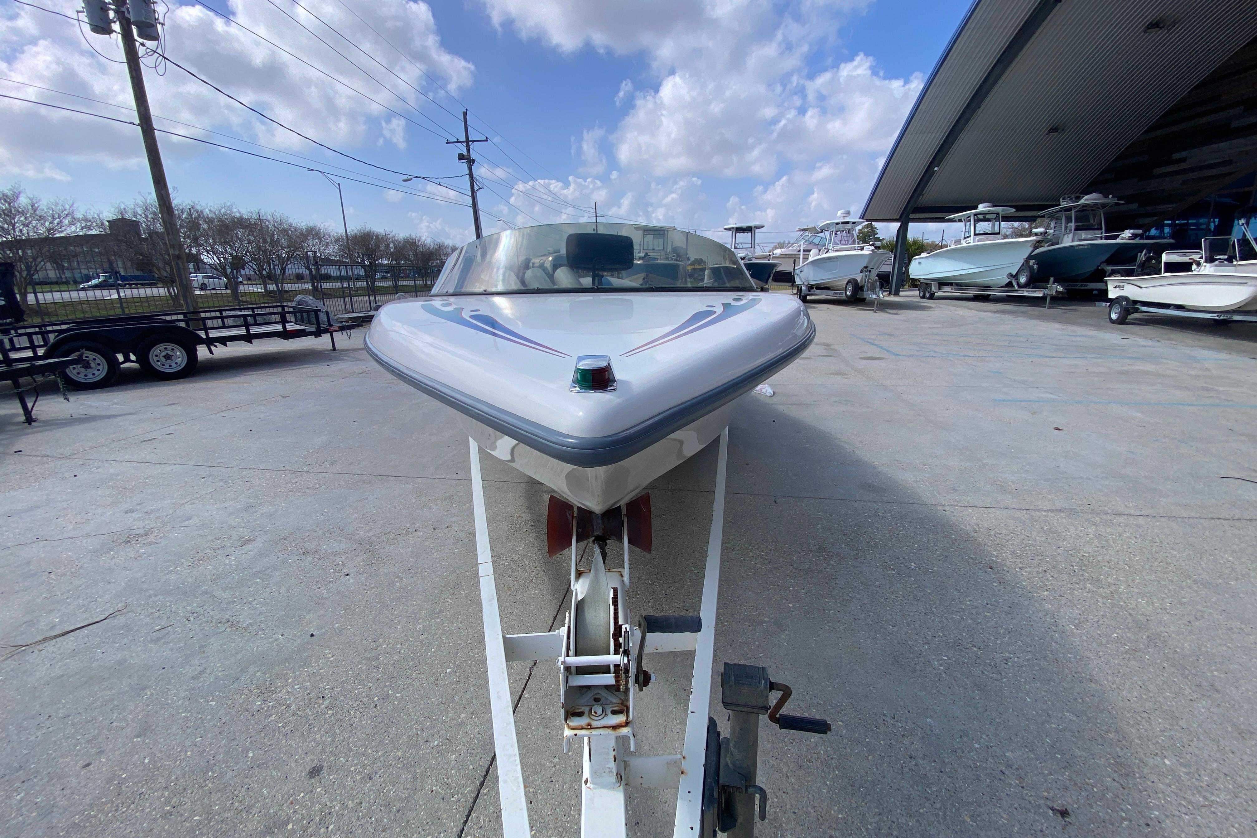 1997 Malibu Tantrum boat on trailer, parked outdoors under a cloudy sky.
