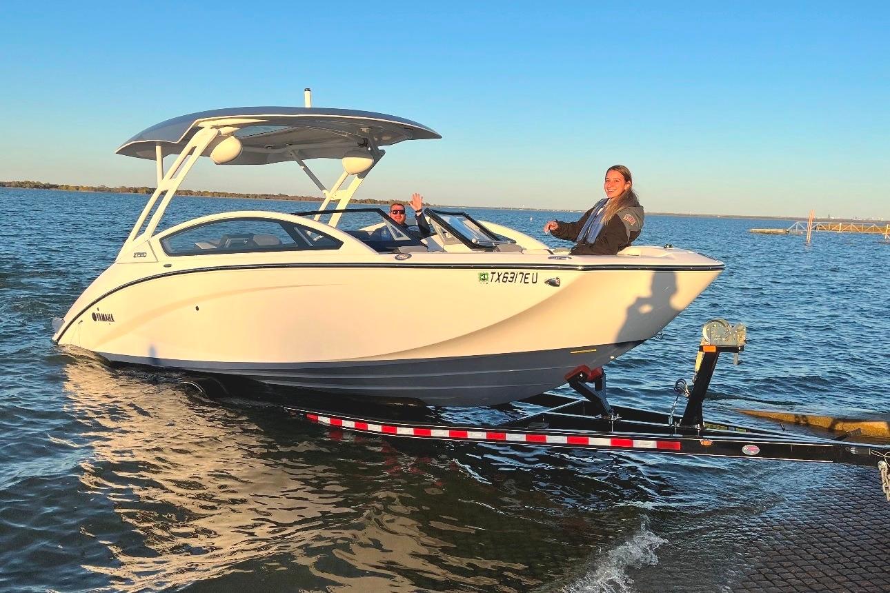 2021 Yamaha Boats 275SD on trailer, two people aboard, near water.