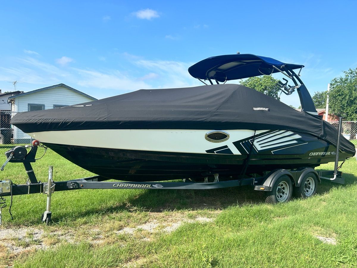 A 2016 Chaparral Vortex 243 VRX boat on a trailer, parked on grass.