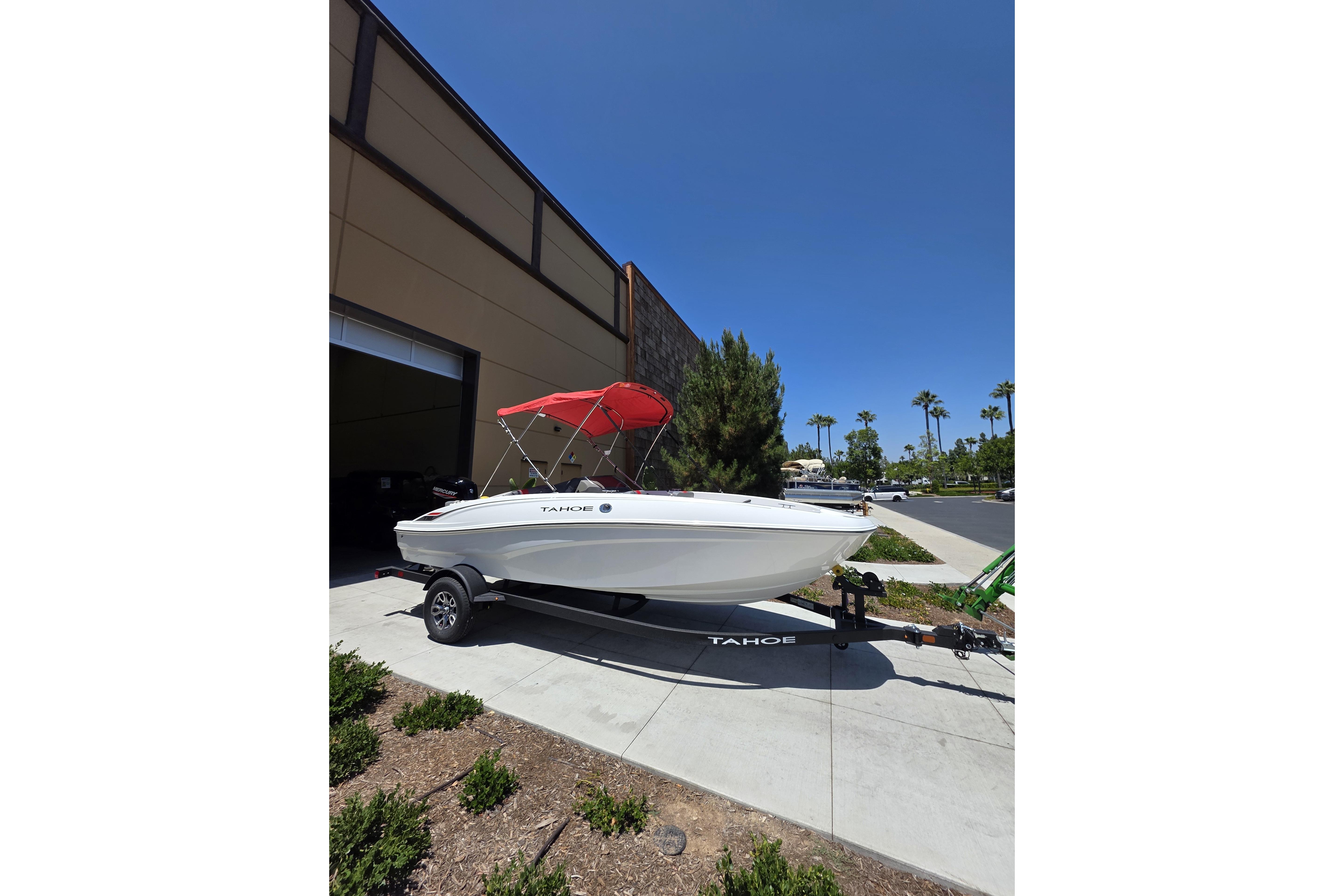 2026 Tahoe T18 boat with red canopy parked outside a building.