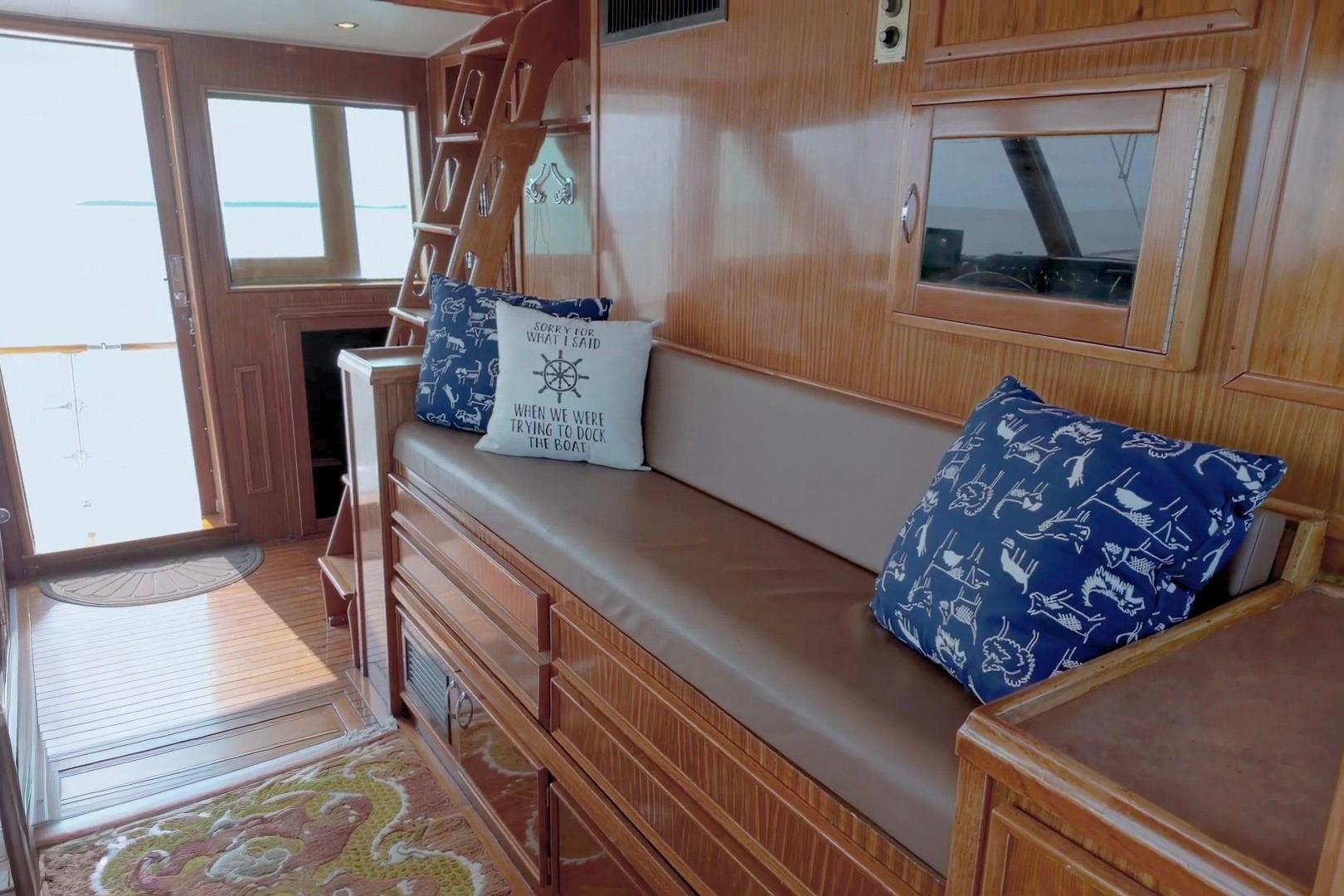 Interior of 1980 Hatteras 70 Motor Yacht with wooden decor and nautical-themed cushions.