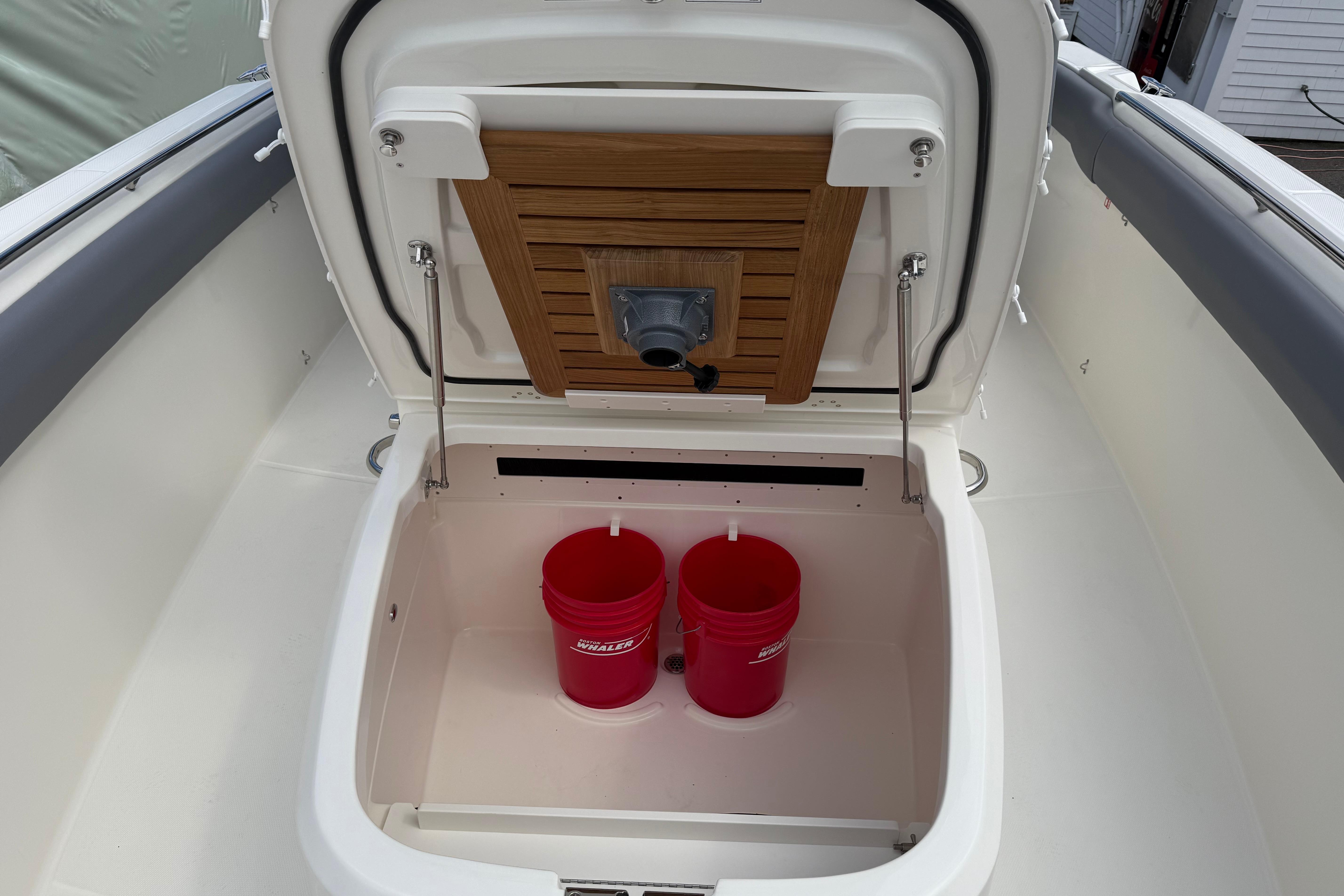 Storage compartment on 2026 Boston Whaler 330 Outrage with red buckets inside.