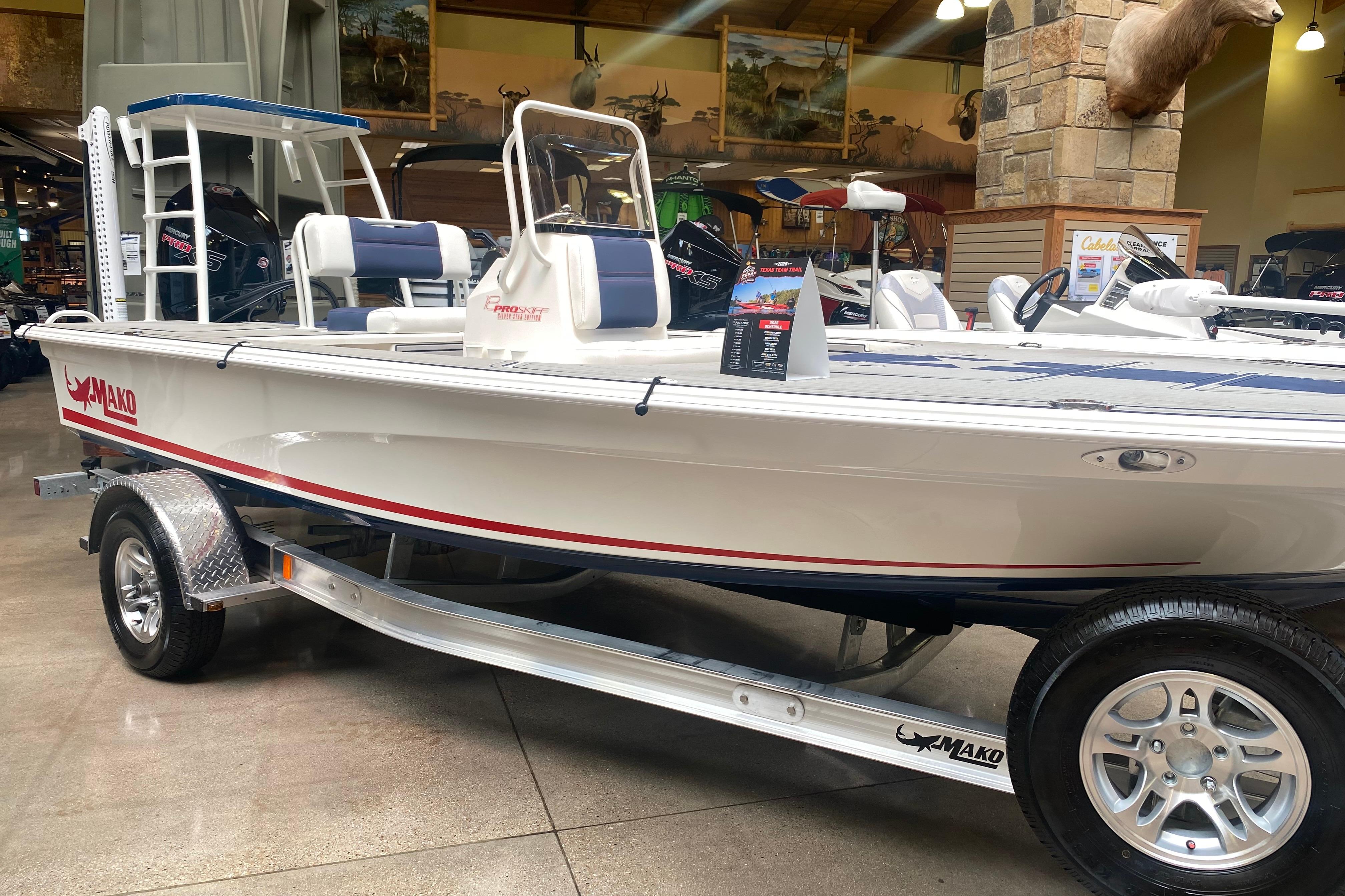 2025 Mako 18 Pro Skiff Patriot Edition boat displayed indoors on a trailer.