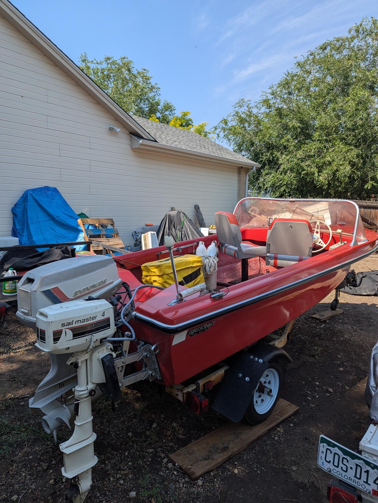 A red 1972 14' Swiss Craft runabout is on a trailer outdoors.
