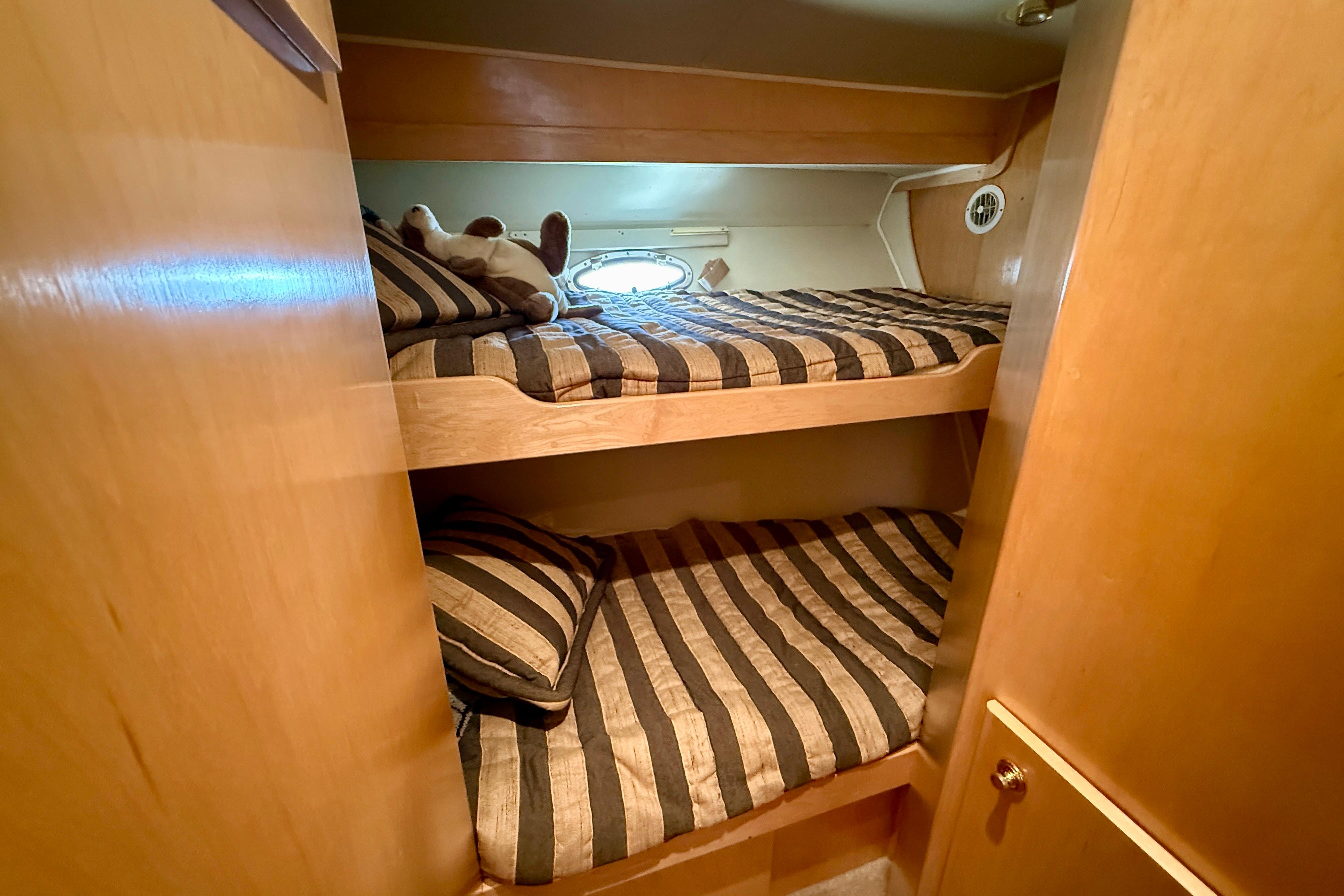 Bunk beds in 1997 Navigator Pilothouse yacht cabin with striped bedding and wooden interior.