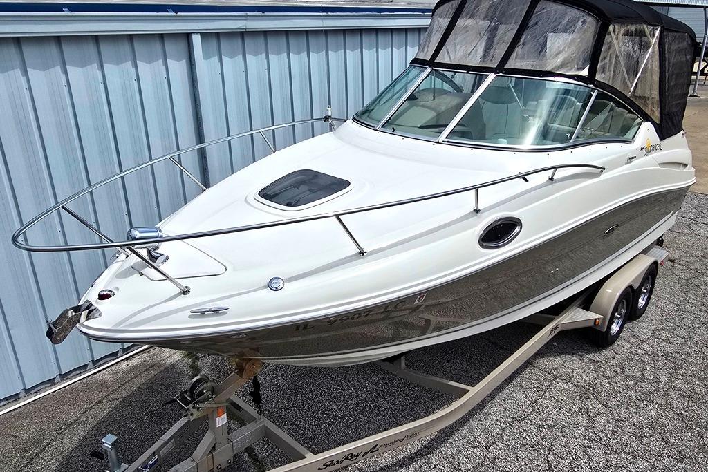 2006 Sea Ray 240 Sundancer boat on trailer, parked near a metal building.