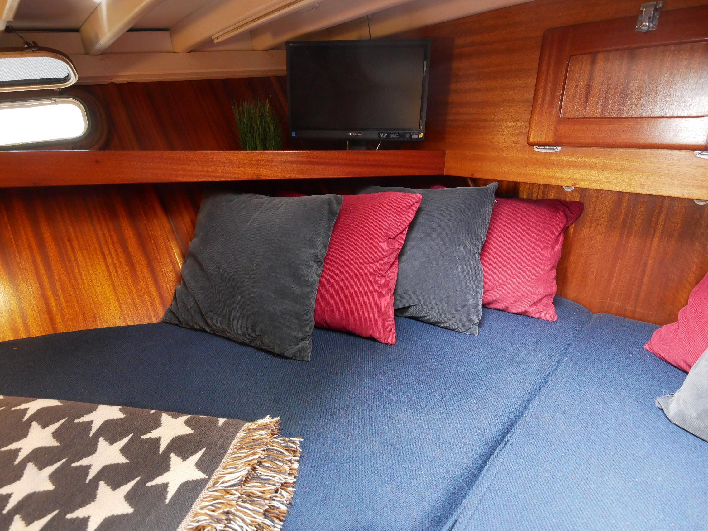 Cozy cabin interior of 1964 Egg Harbor 37 Convertible Sedan with pillows and TV.