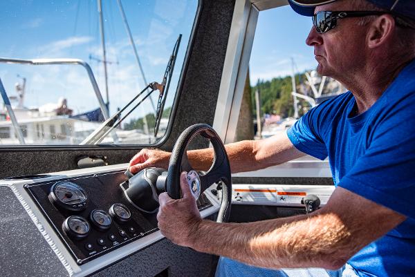 Man steering 2023 Spartan 220 Maximus Pro boat on a sunny day.