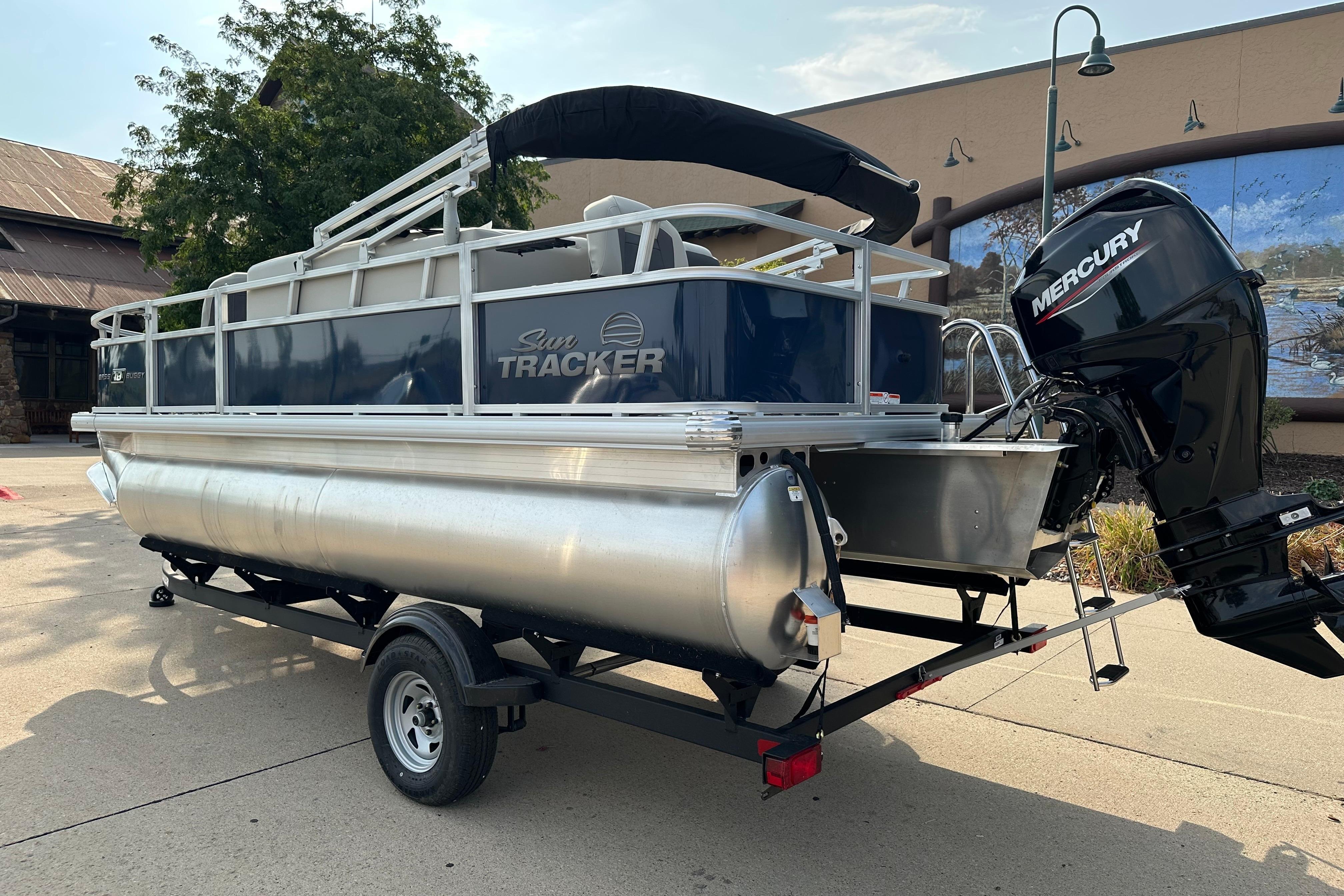 2026 Sun Tracker Bass Buggy 18 DLX pontoon boat with Mercury outboard motor on trailer.
