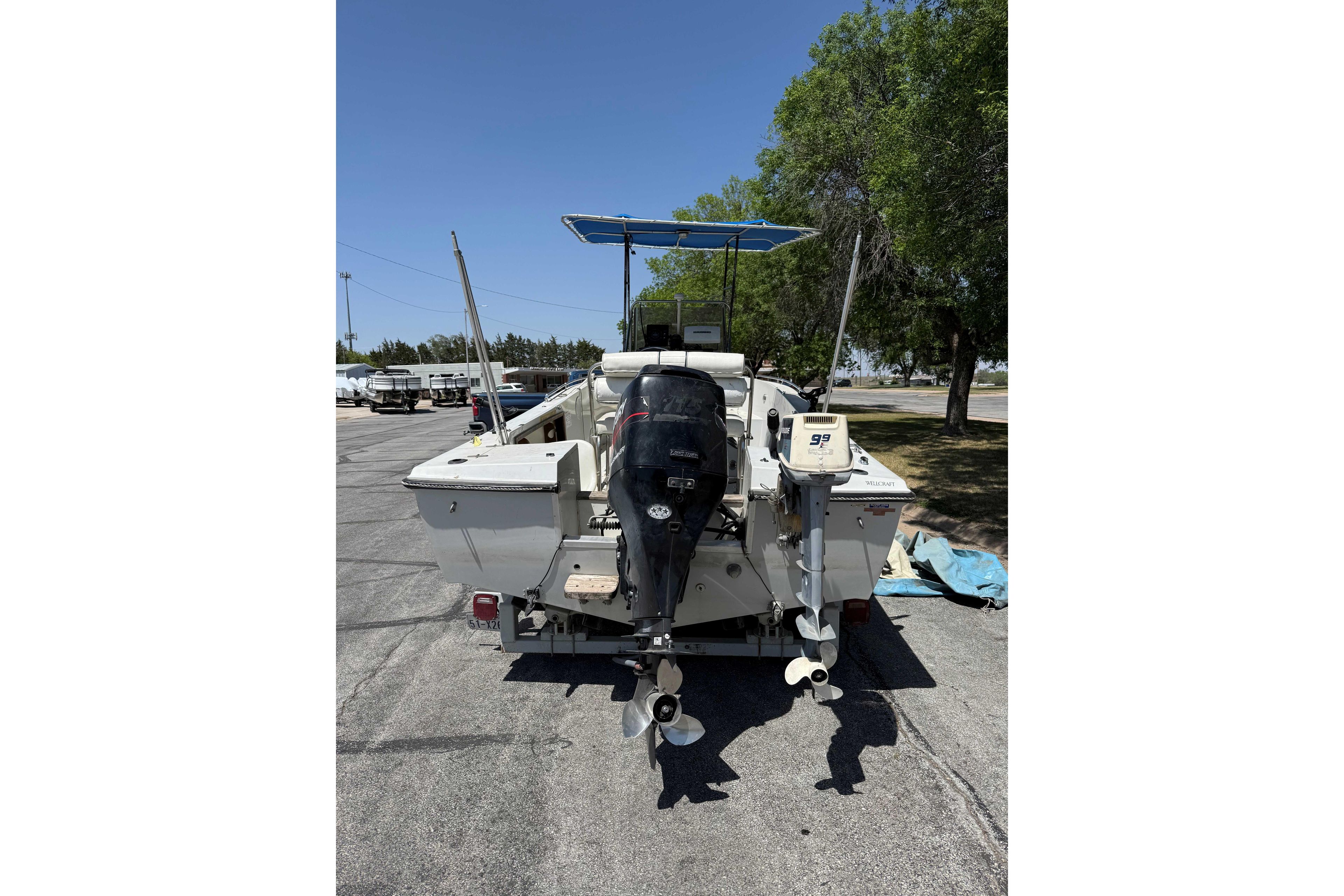 1985 Wellcraft 180 Fisherman boat with dual outboard motors, parked outdoors.