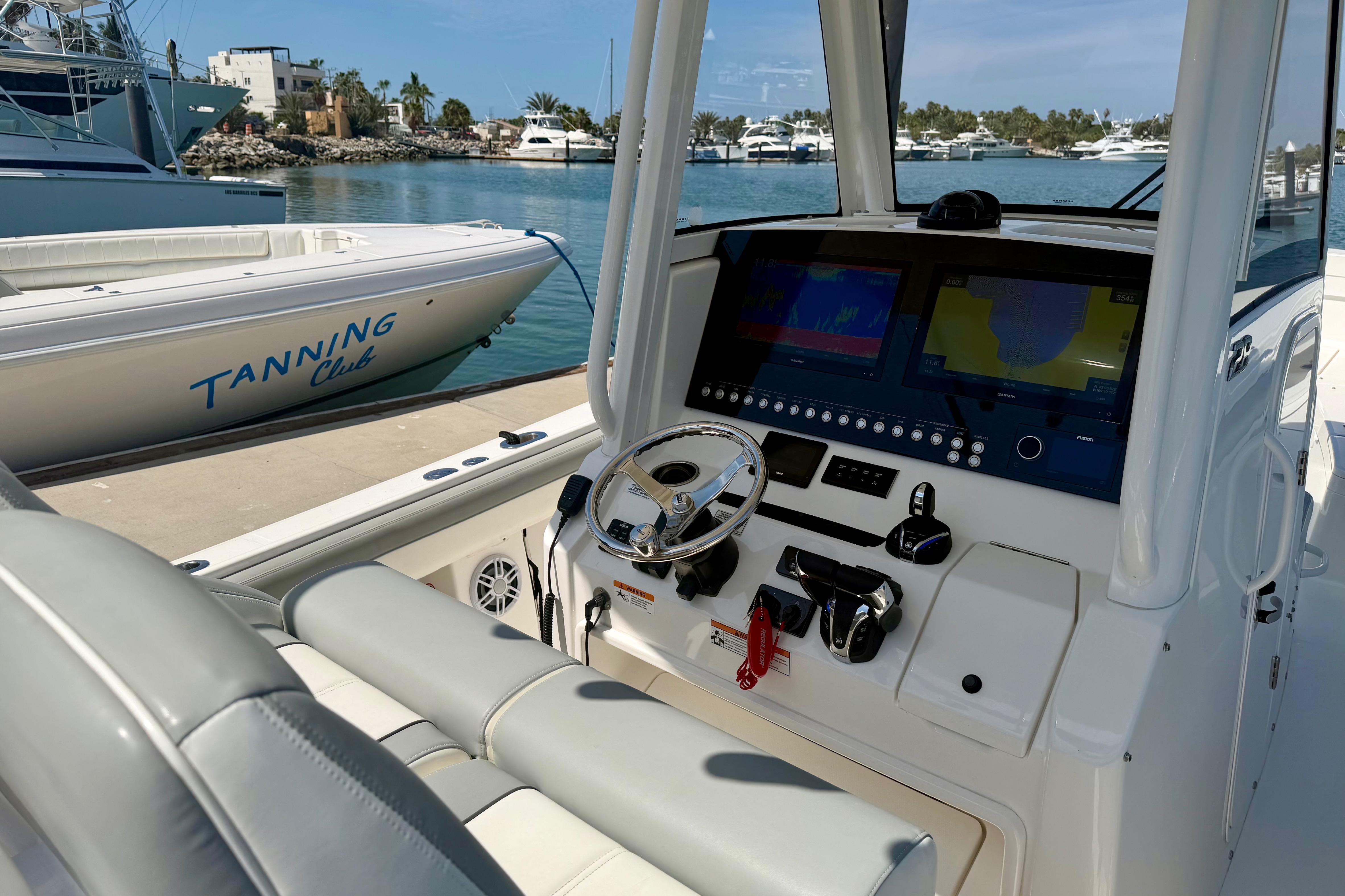 2022 Regulator 28 boat dashboard with advanced navigation system, docked near Tanning Club boat.