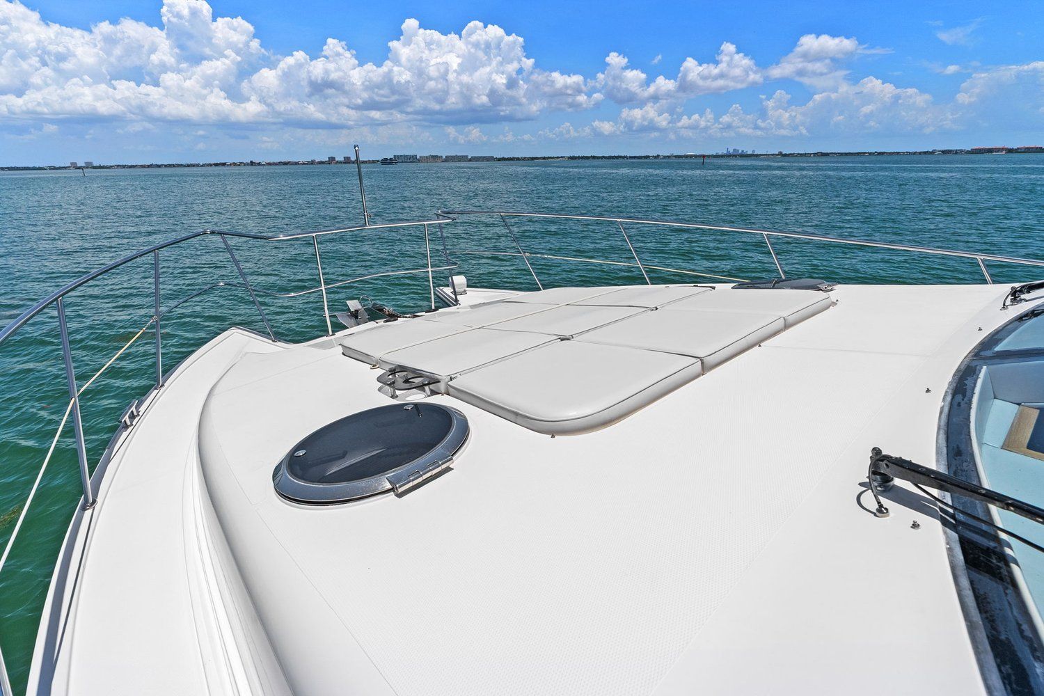 The deck of a catamaran with sunbathing areas, surrounded by blue water and a clear sky.