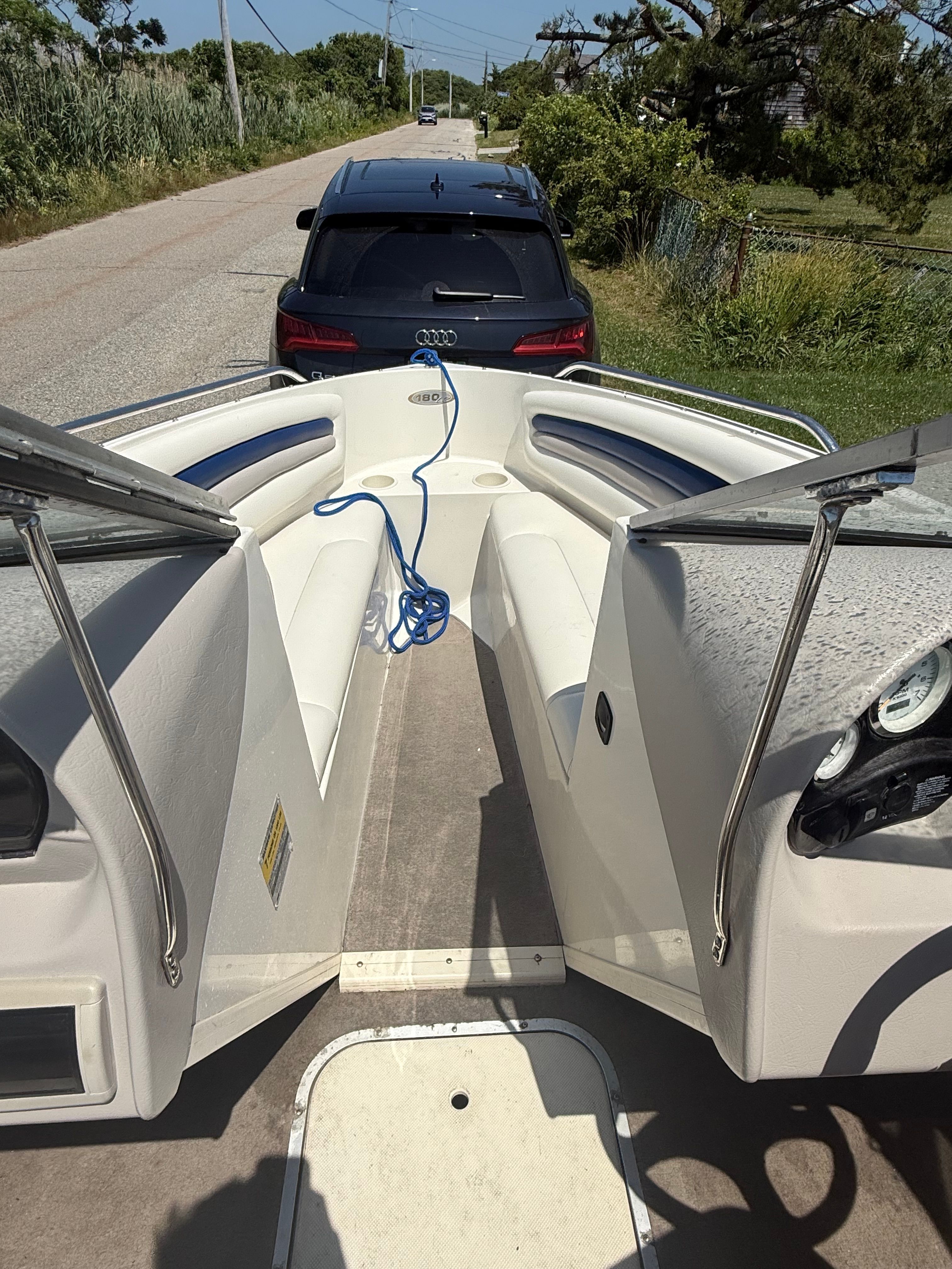 A 2003 Stingray 180 LS/LX boat on a trailer, with a car in the background.