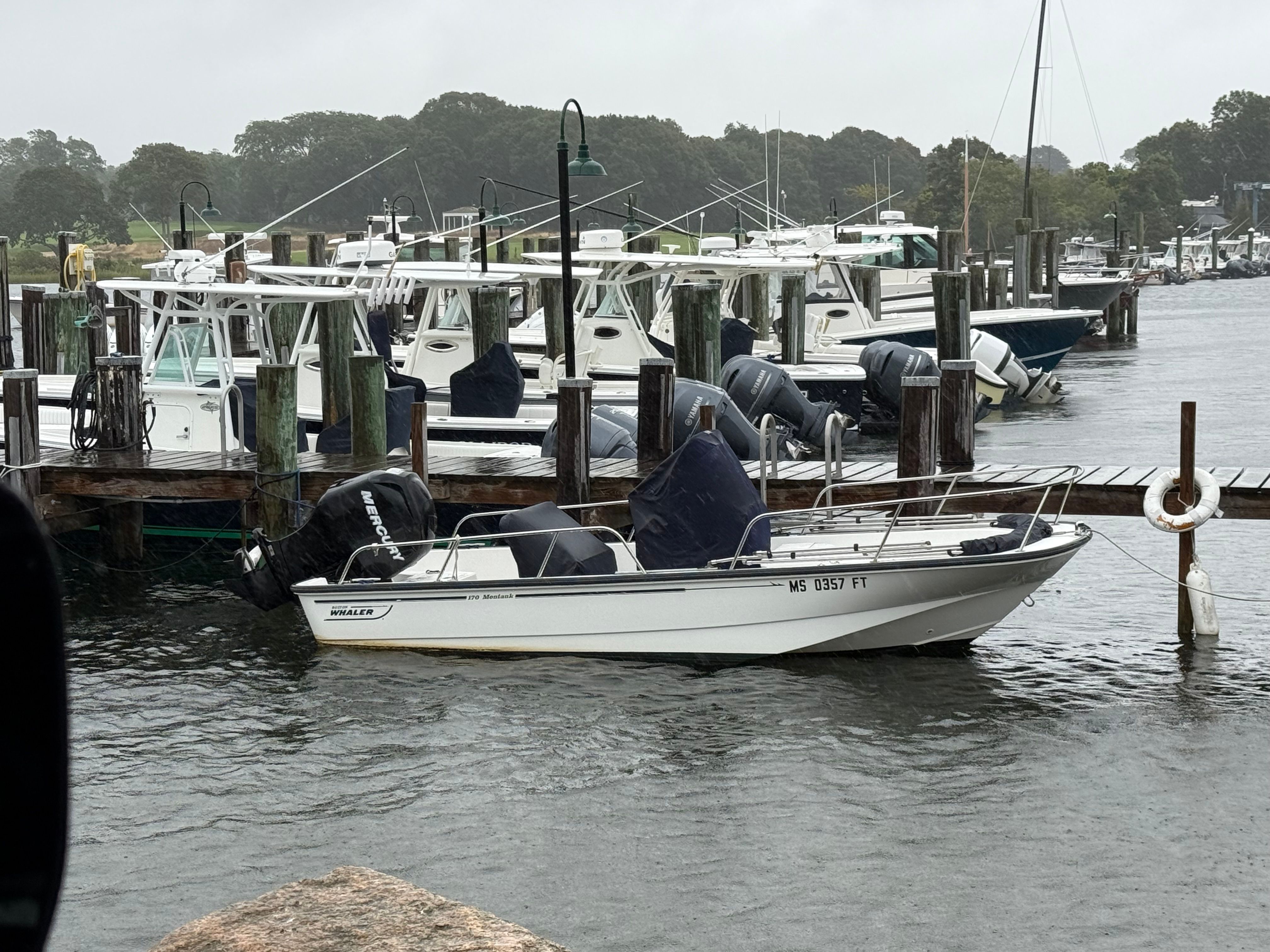 A 2011 Boston Whaler 170 Montauk is docked in a calm harbor.
