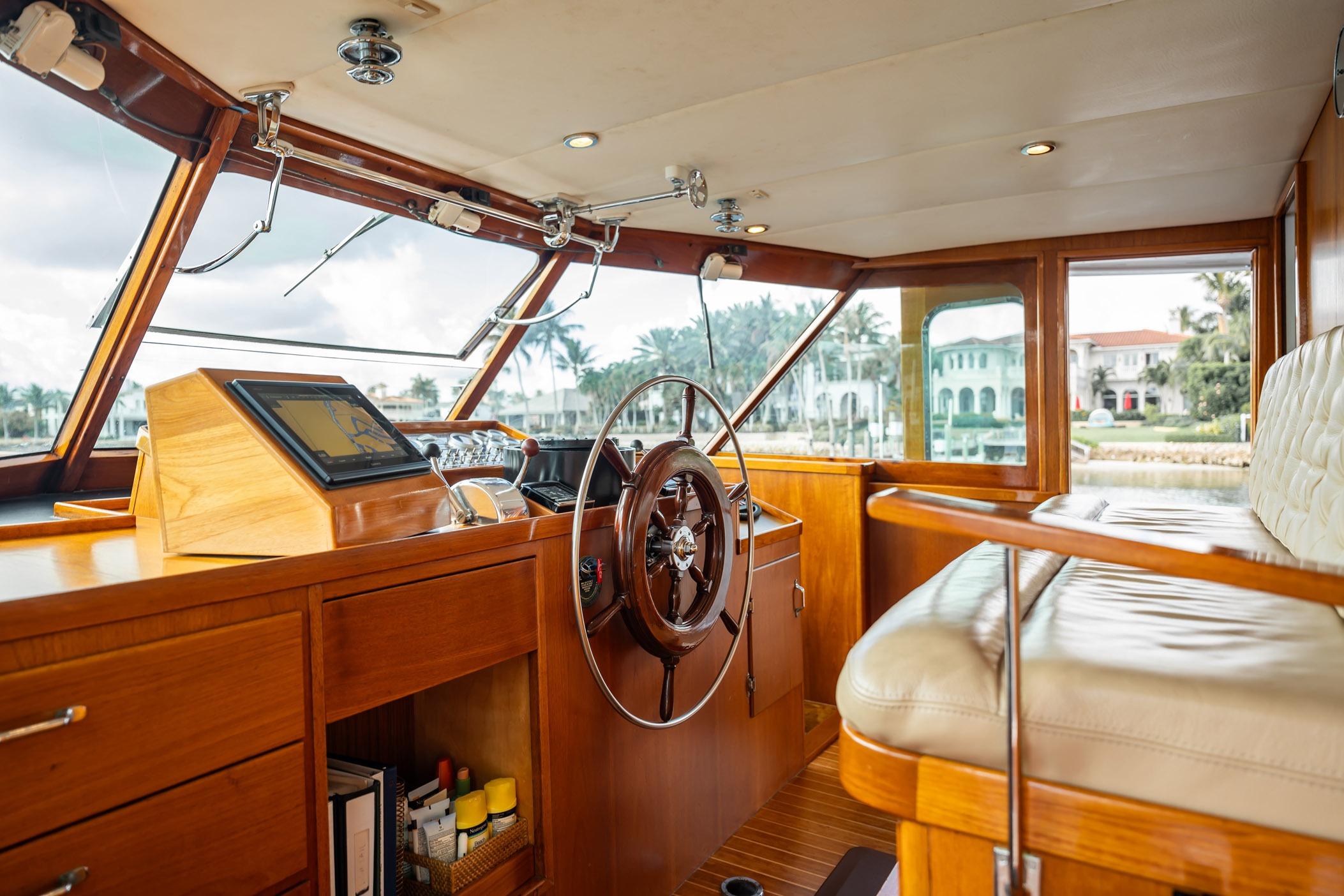 Interior of 1972 Trumpy 72 Motor Yacht with wooden helm and plush seating.