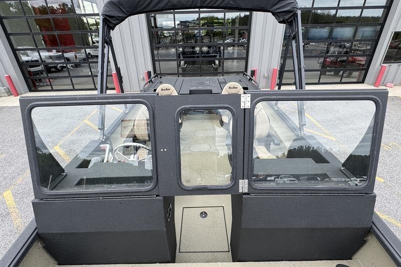 2026 SeaArk Predator 300 AK boat with glass doors and seating, parked outside a building.