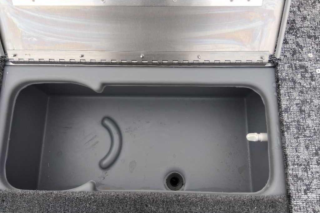 Open storage compartment in 2026 Tracker Pro 170 boat, featuring a gray interior and carpeted edges.