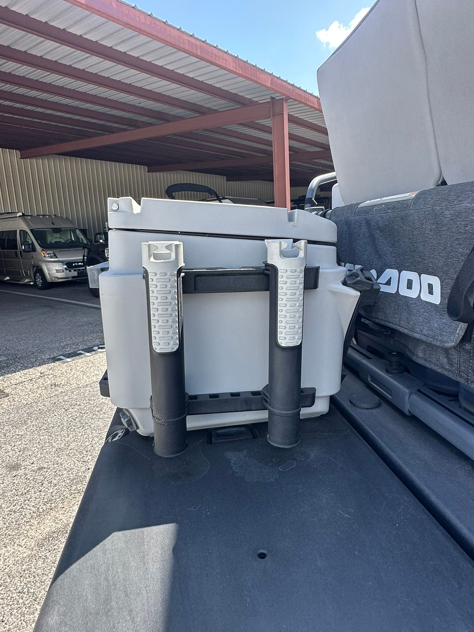 A gray cooler on a Sea-Doo boat, parked under a covered area.