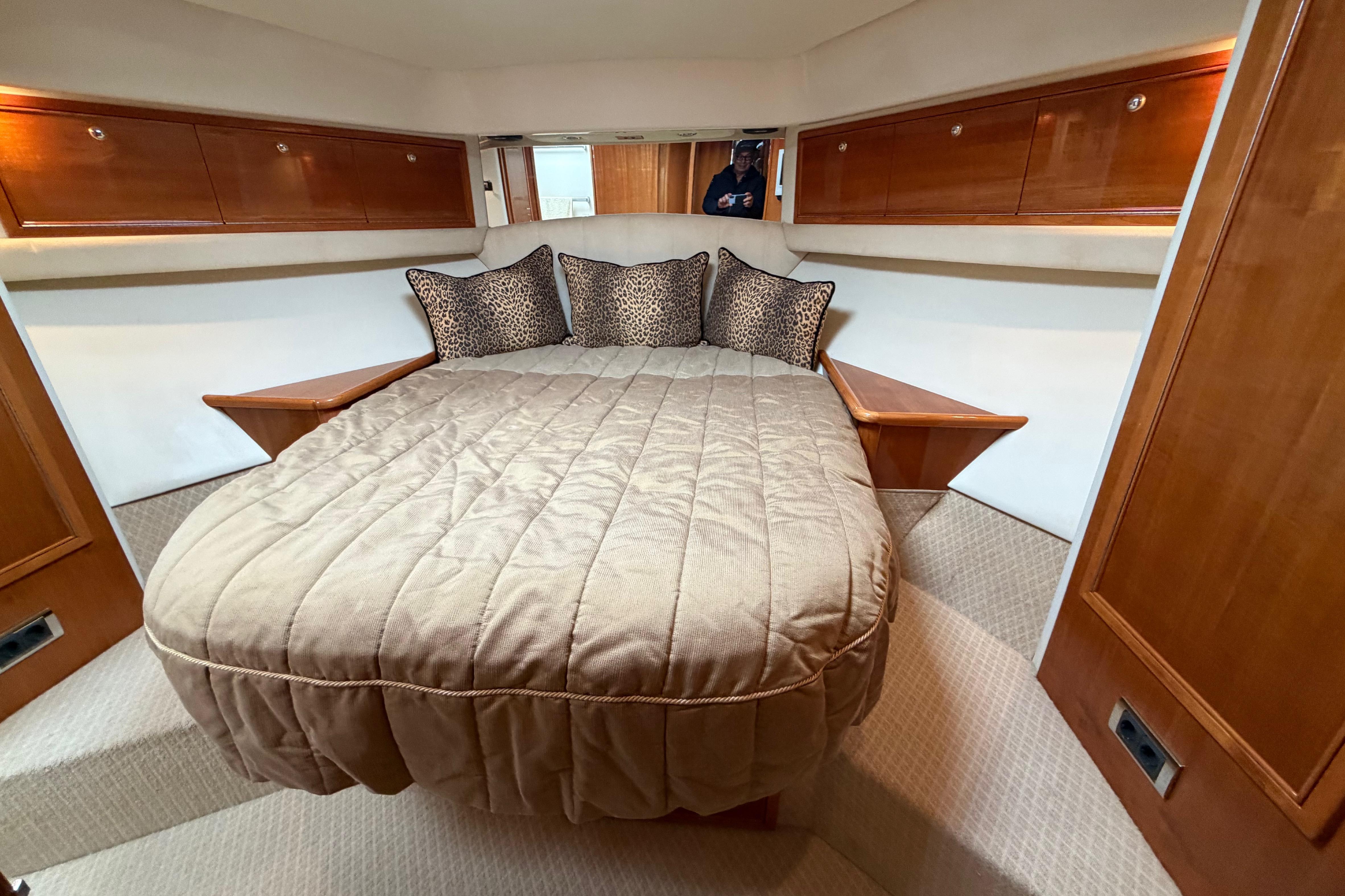 Luxurious bedroom interior of 2004 Riviera 60 Flybridge yacht with plush bedding.