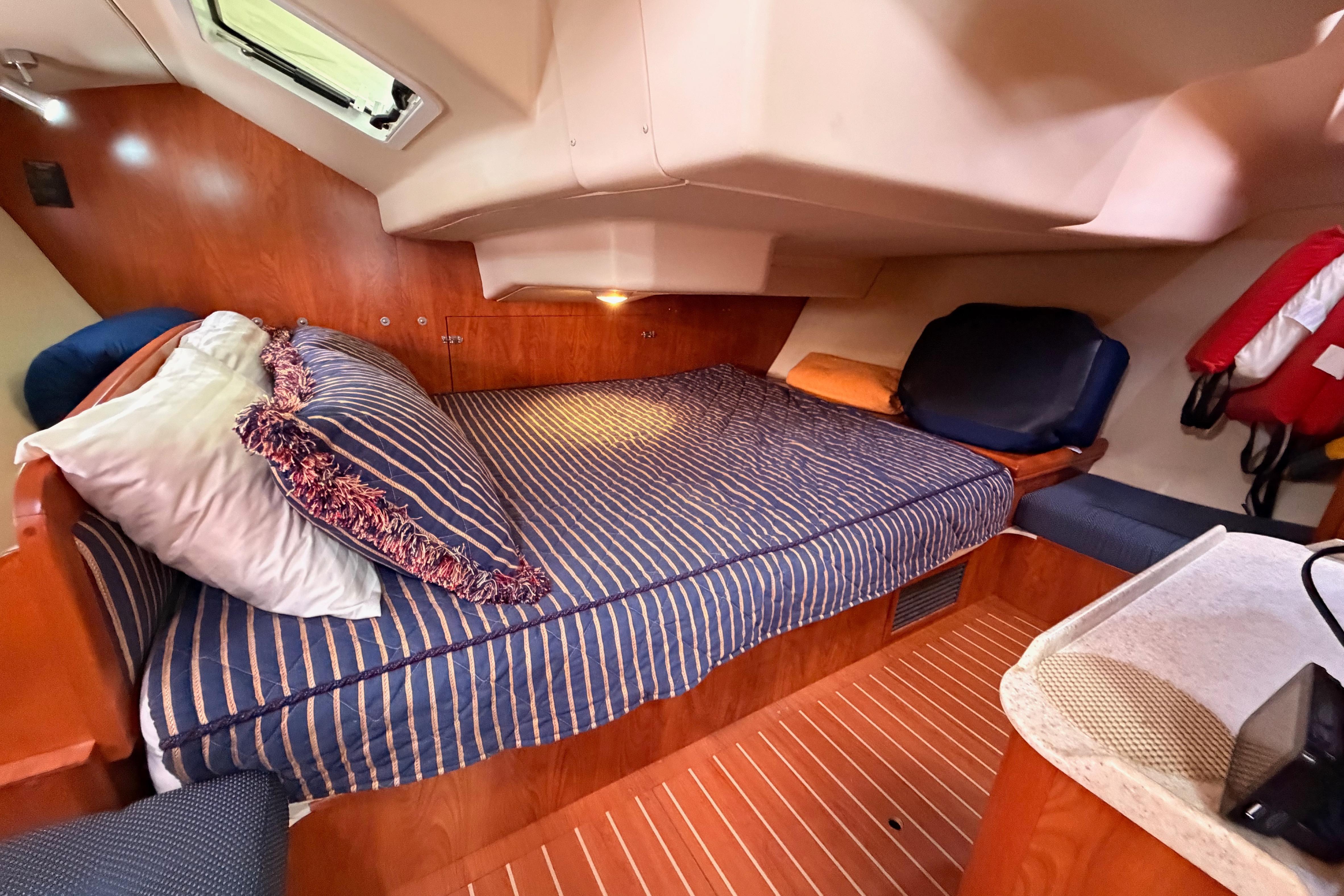 Cozy cabin interior of 2009 Hunter 38 sailboat with striped bedding and wood finish.
