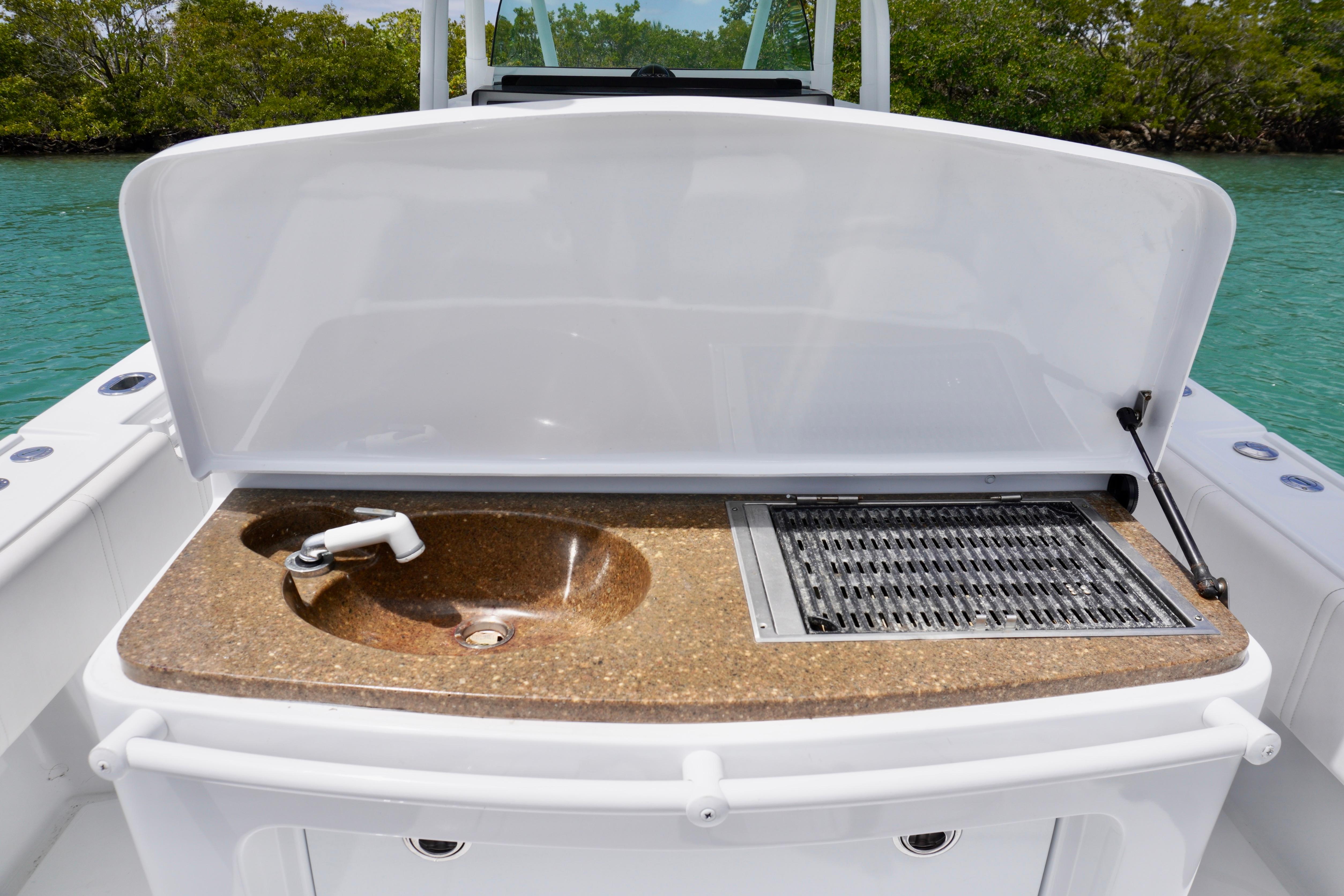 Boat sink and grill on 2013 Contender 35 LS, with open cover, near water.