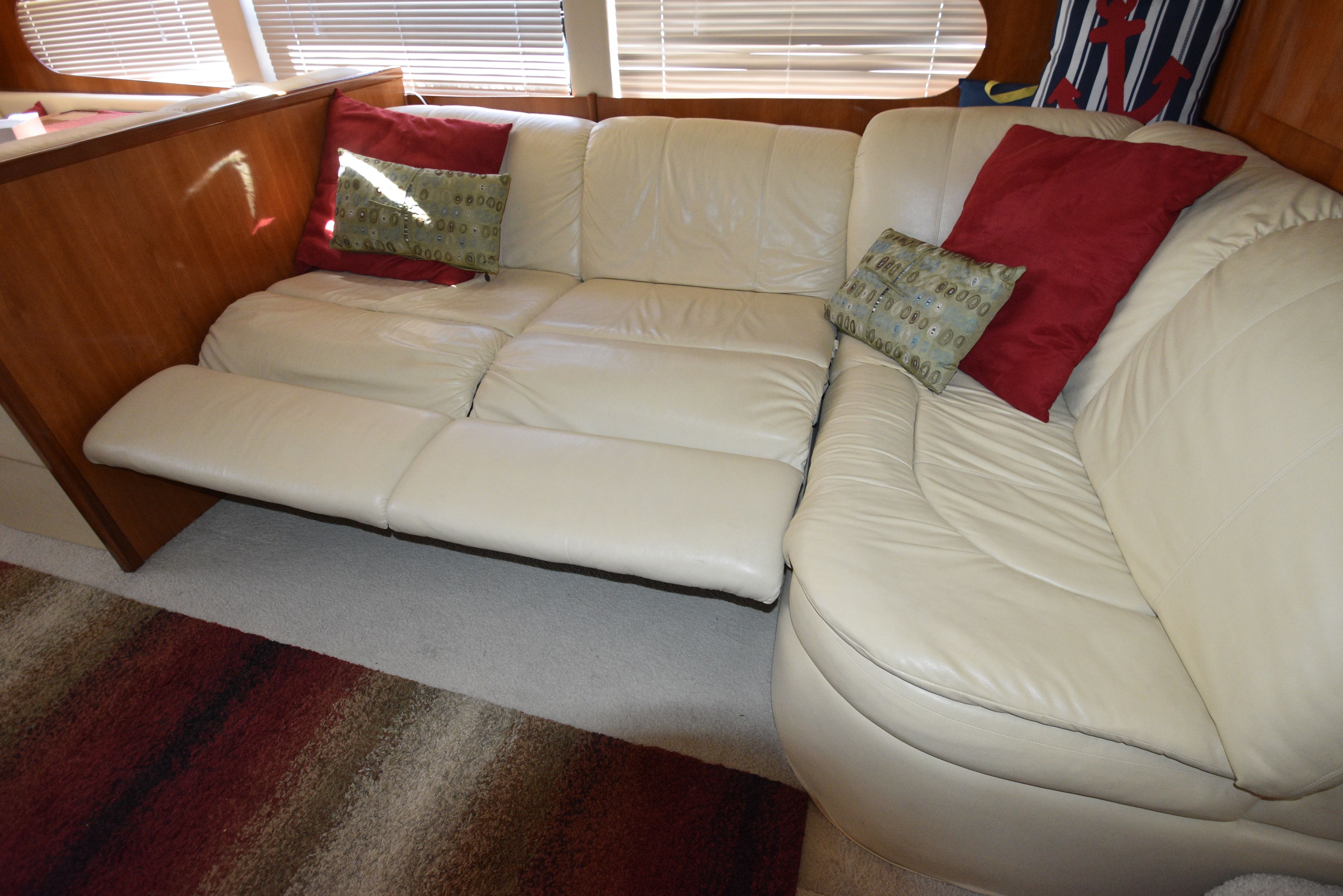 Interior of a 2004 Carver 466 Motor Yacht with cream leather sofa and red cushions.