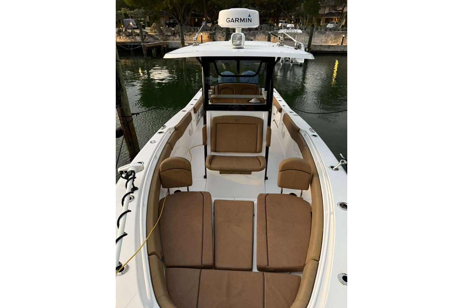 2021 Sea Hunt Gamefish 30 Forward Seating boat with tan cushions, docked by the water.