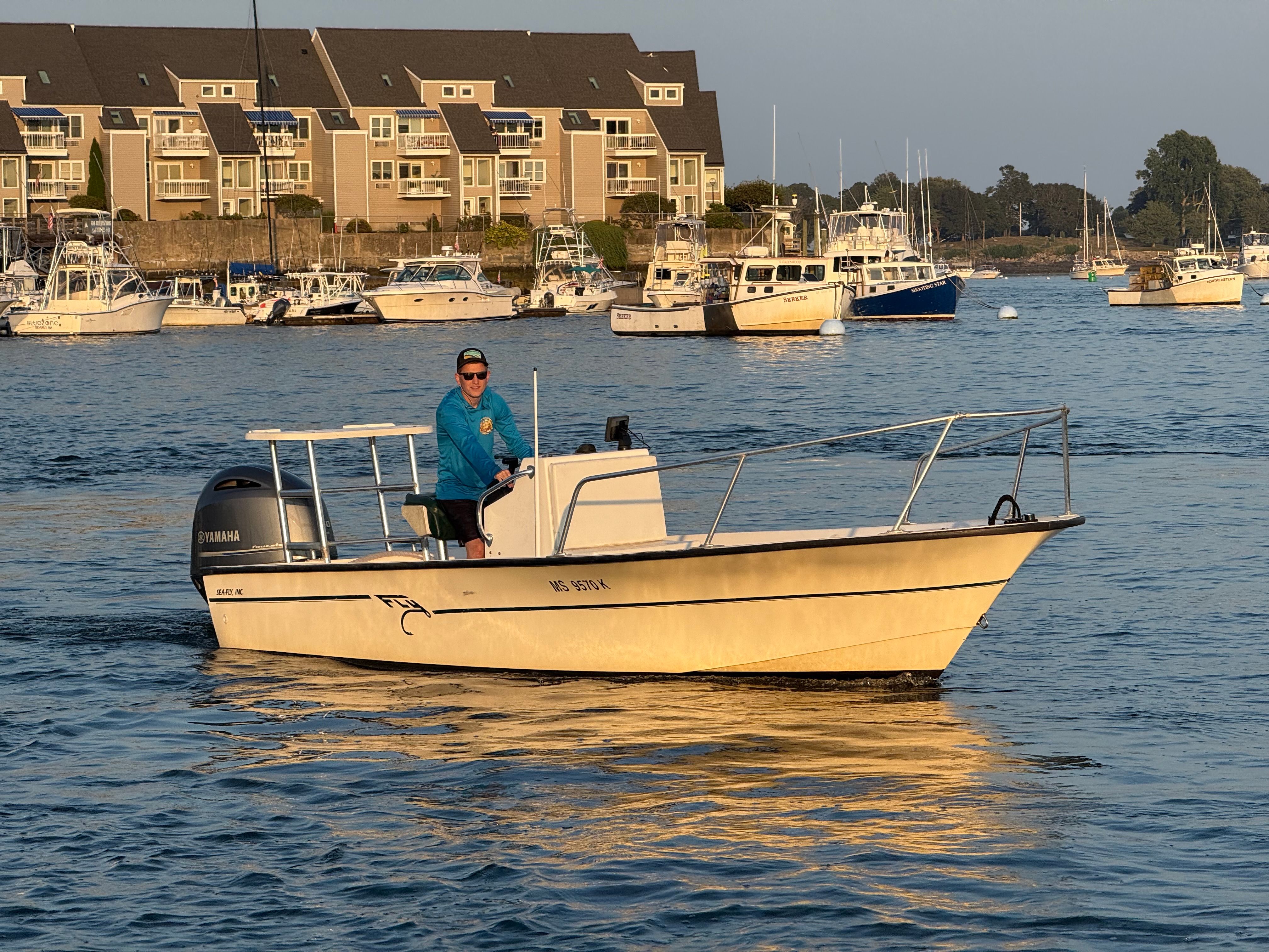 Custom 2004 Sea Fly boat cruising in a marina with waterfront buildings in the background.