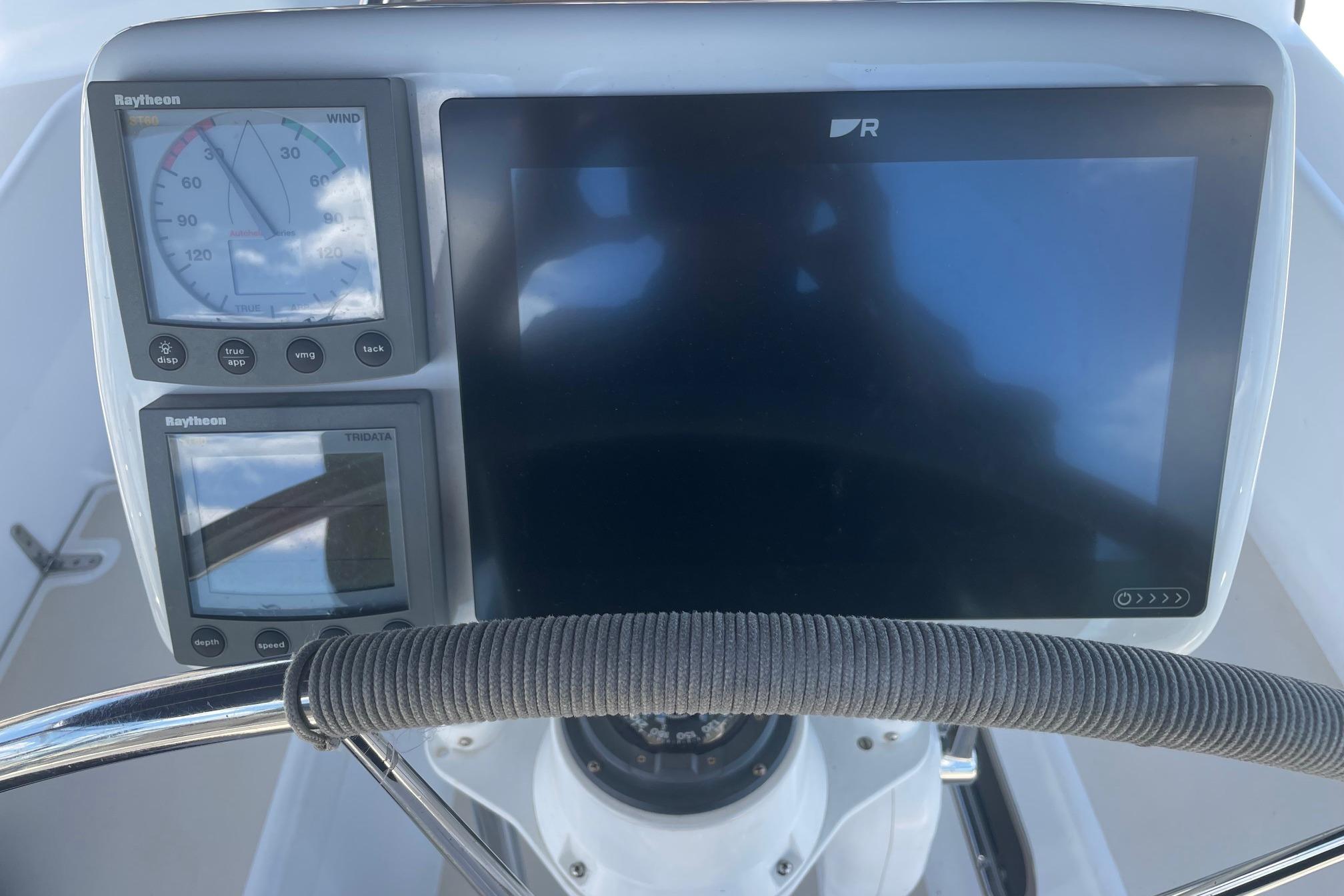 Cockpit instruments of a 2001 Tartan 3700 sailboat, featuring Raytheon displays and steering wheel.
