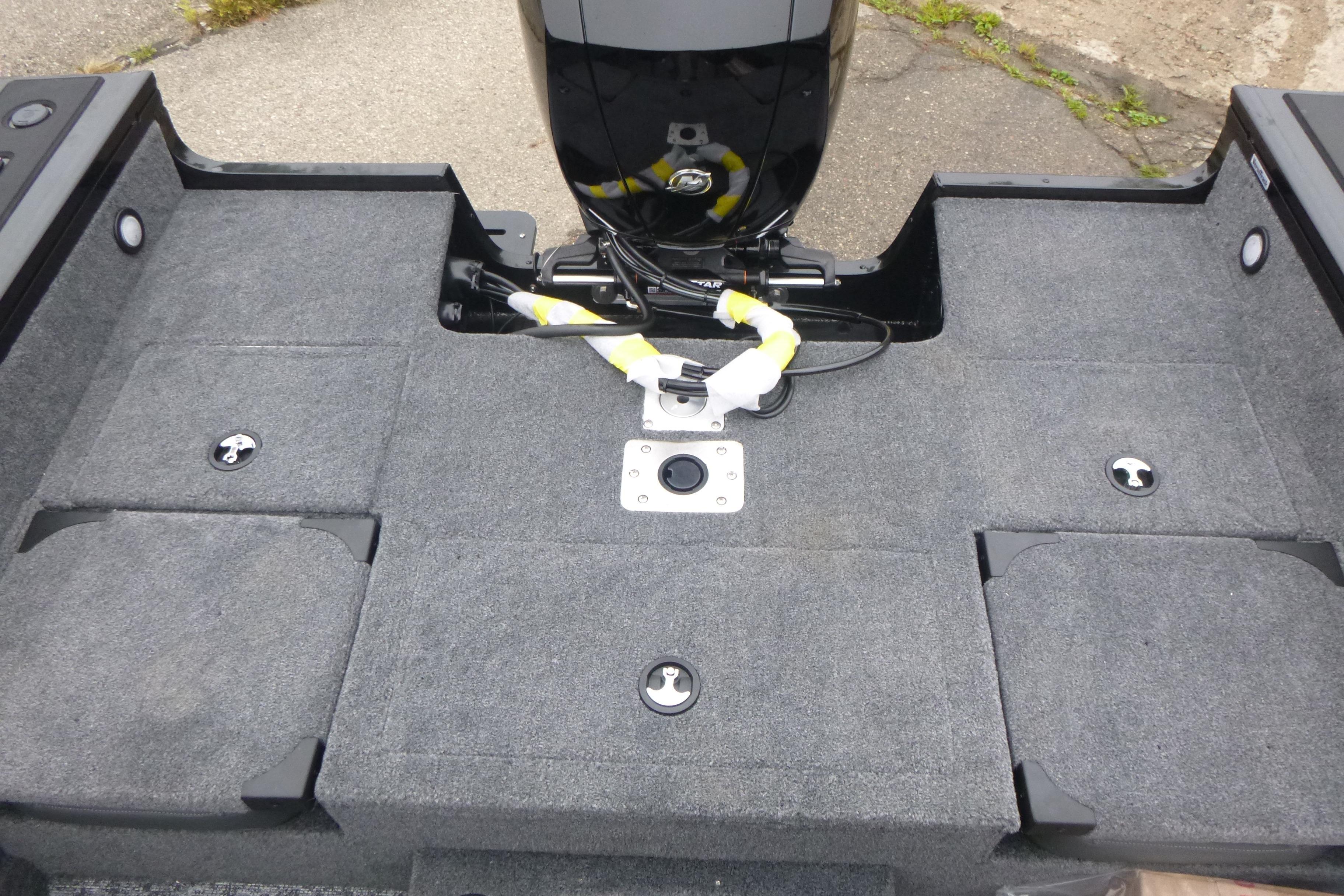 2026 Tracker Targa V-18 Combo boat deck with motor, featuring gray carpeting and storage compartments.