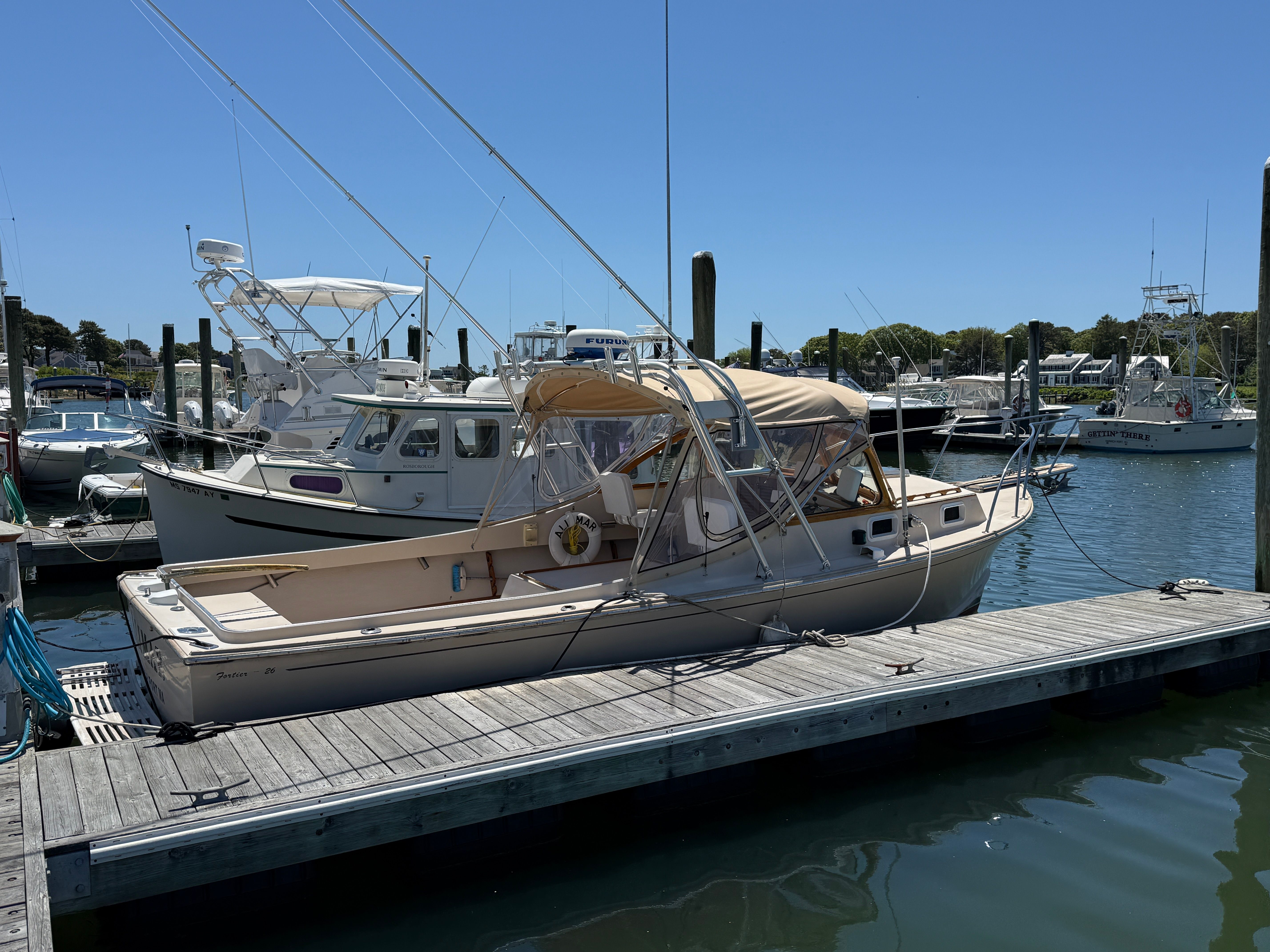 A 1989 Fortier 26 boat docked in a sunny harbor.
