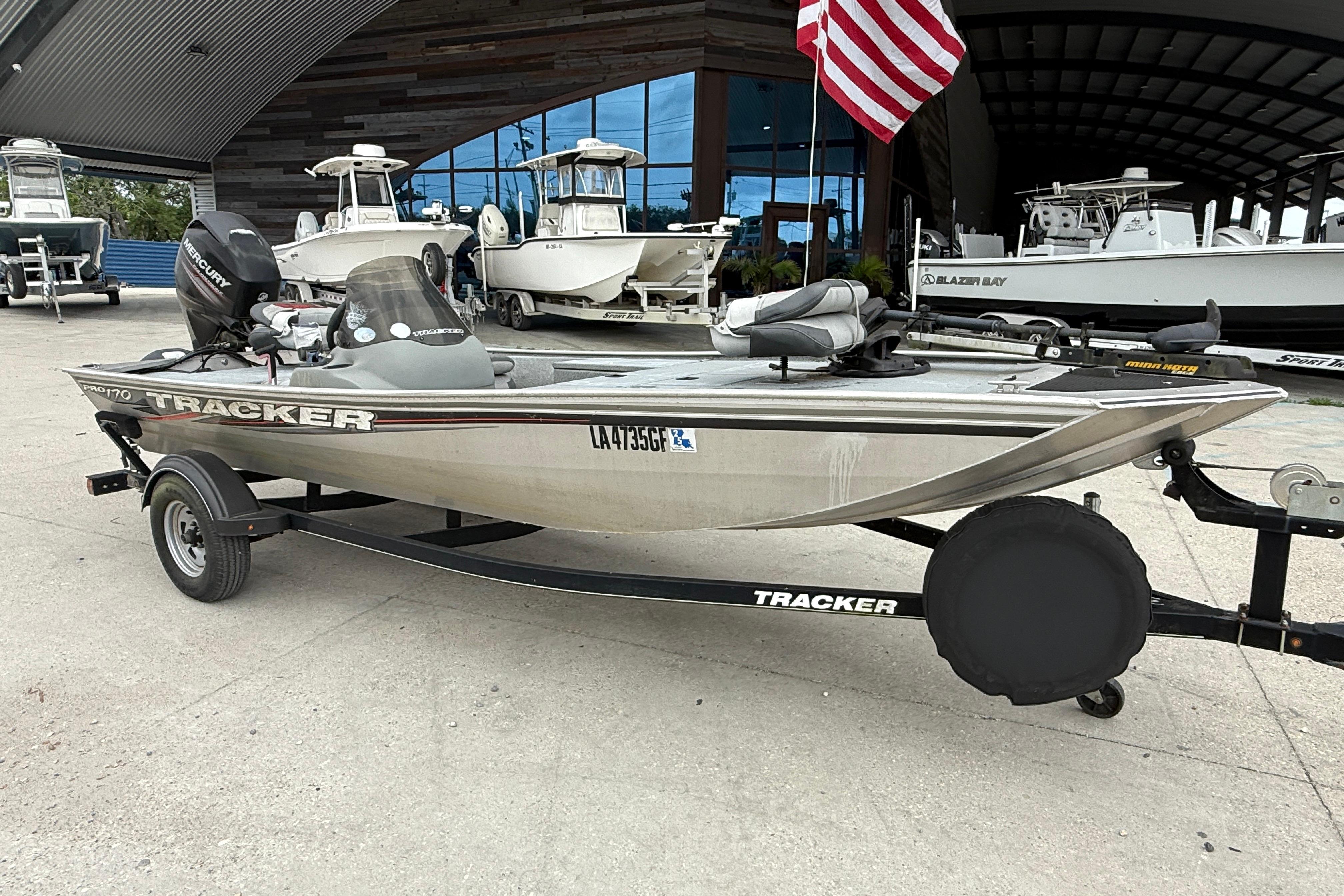 2016 Tracker Pro 170 boat on trailer, parked outside dealership with American flag.