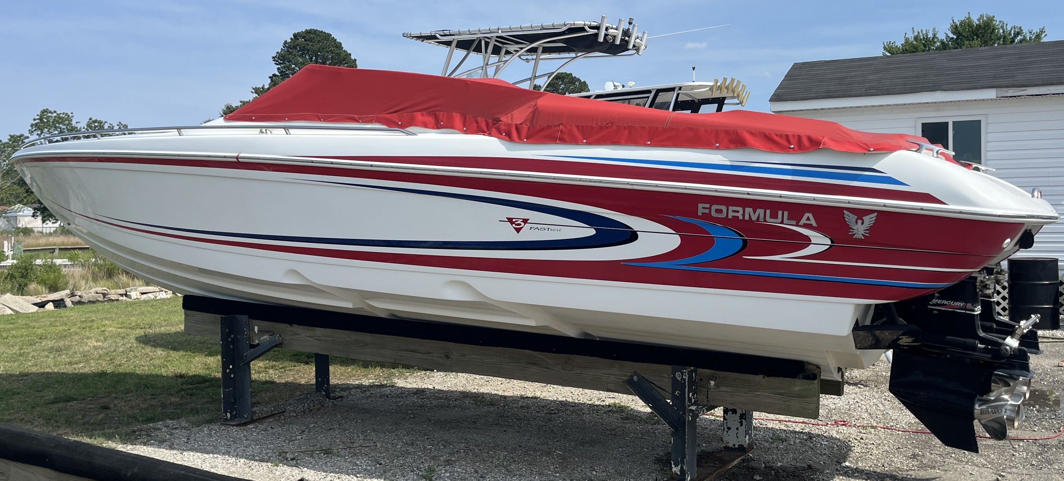 A 2004 Formula 292 FASTech boat with a red cover is on a stand.