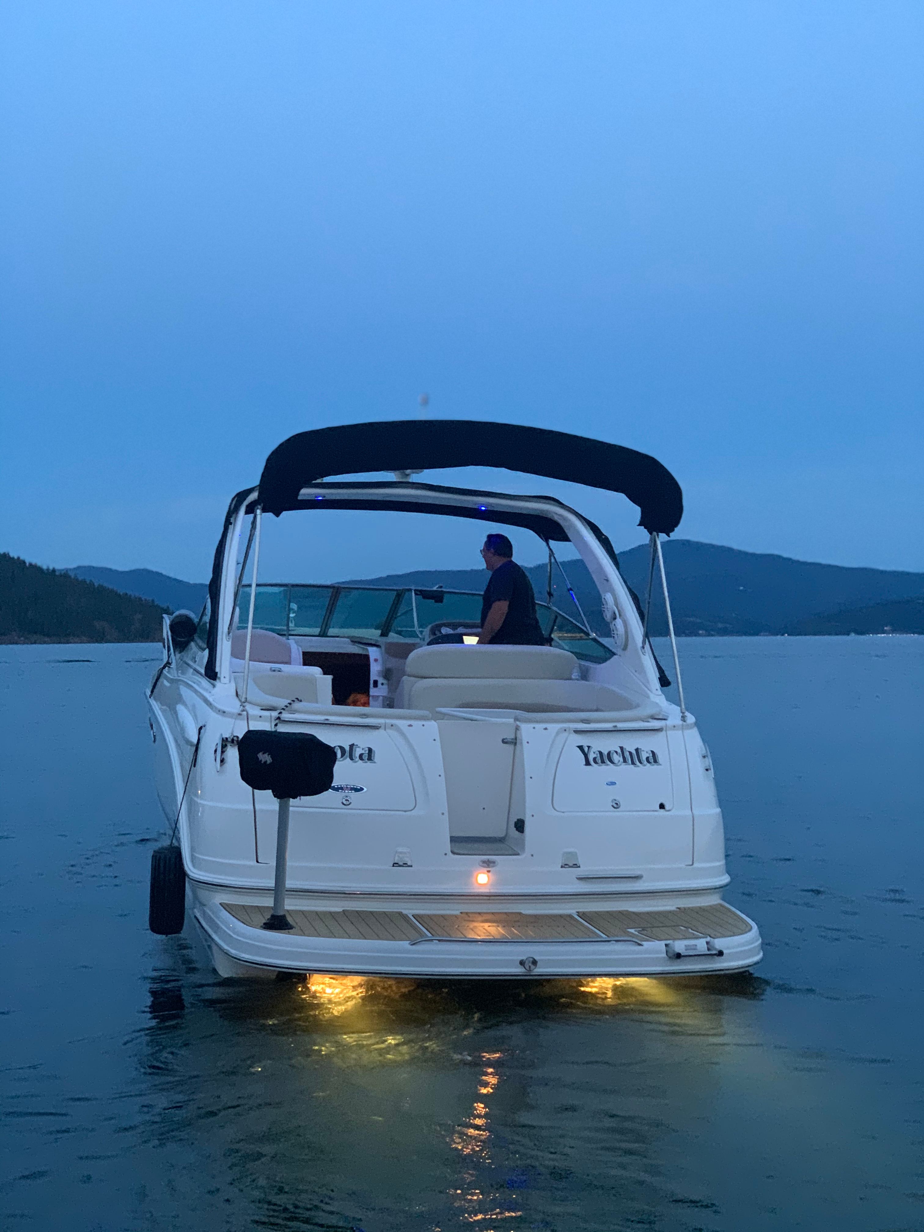 A 2004 Chaparral Signature 330 on calm water at dusk. One person is steering the boat.