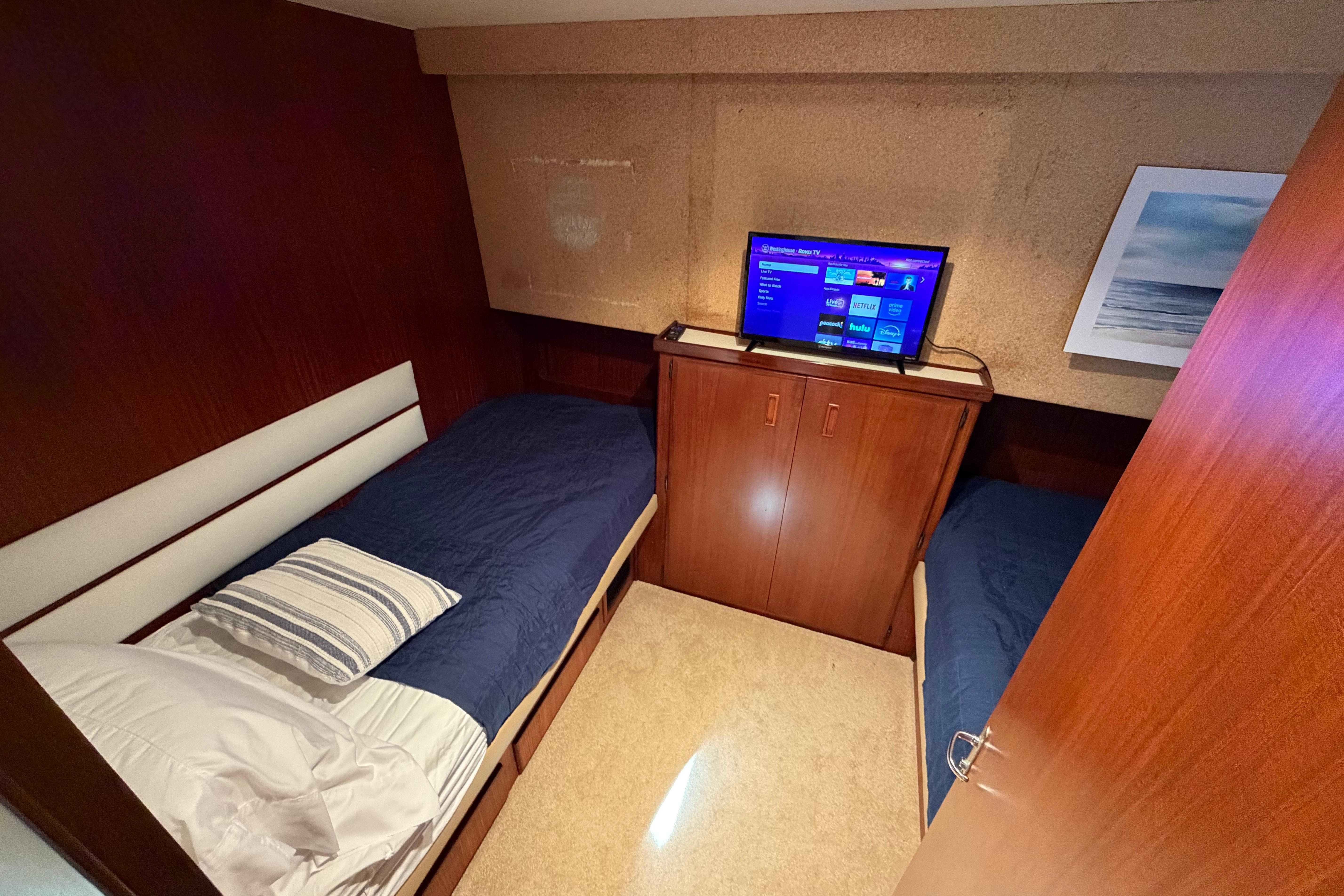 Twin bed cabin in 1991 Hatteras 70 Motor Yacht with TV and ocean artwork.