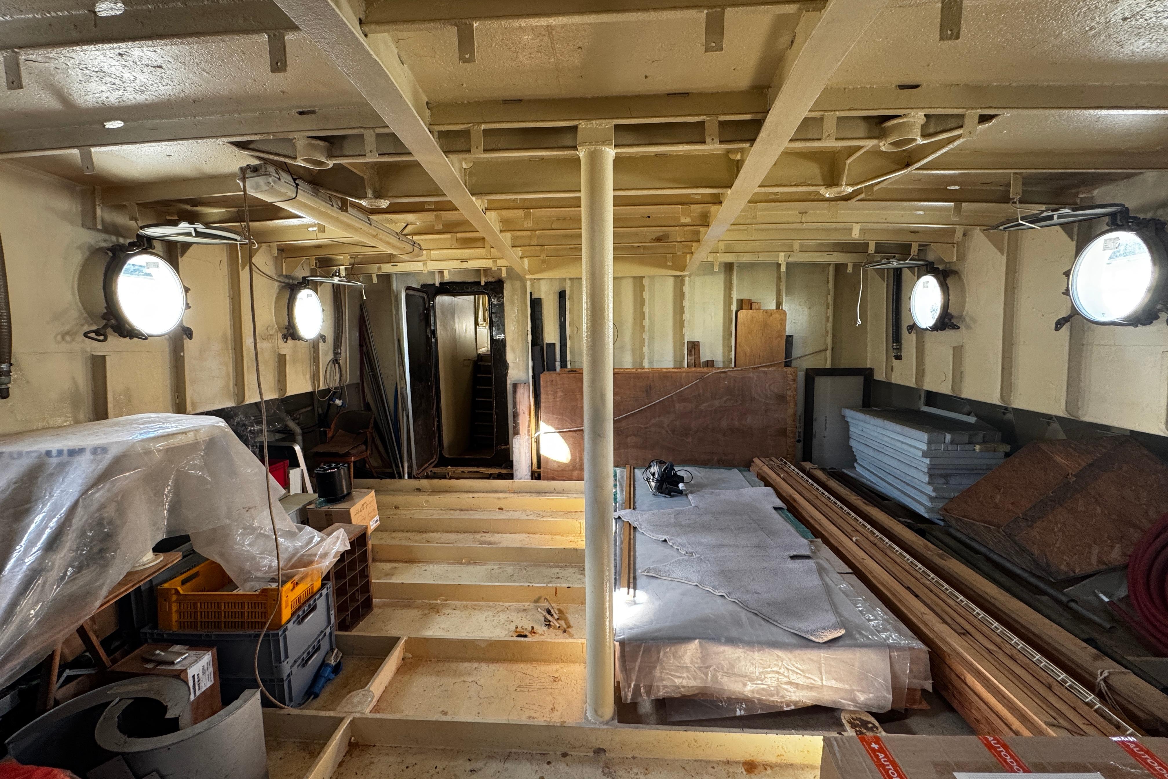 Interior of 1957 Hitzler Rompighiaccio ship under renovation, featuring portholes and construction materials.