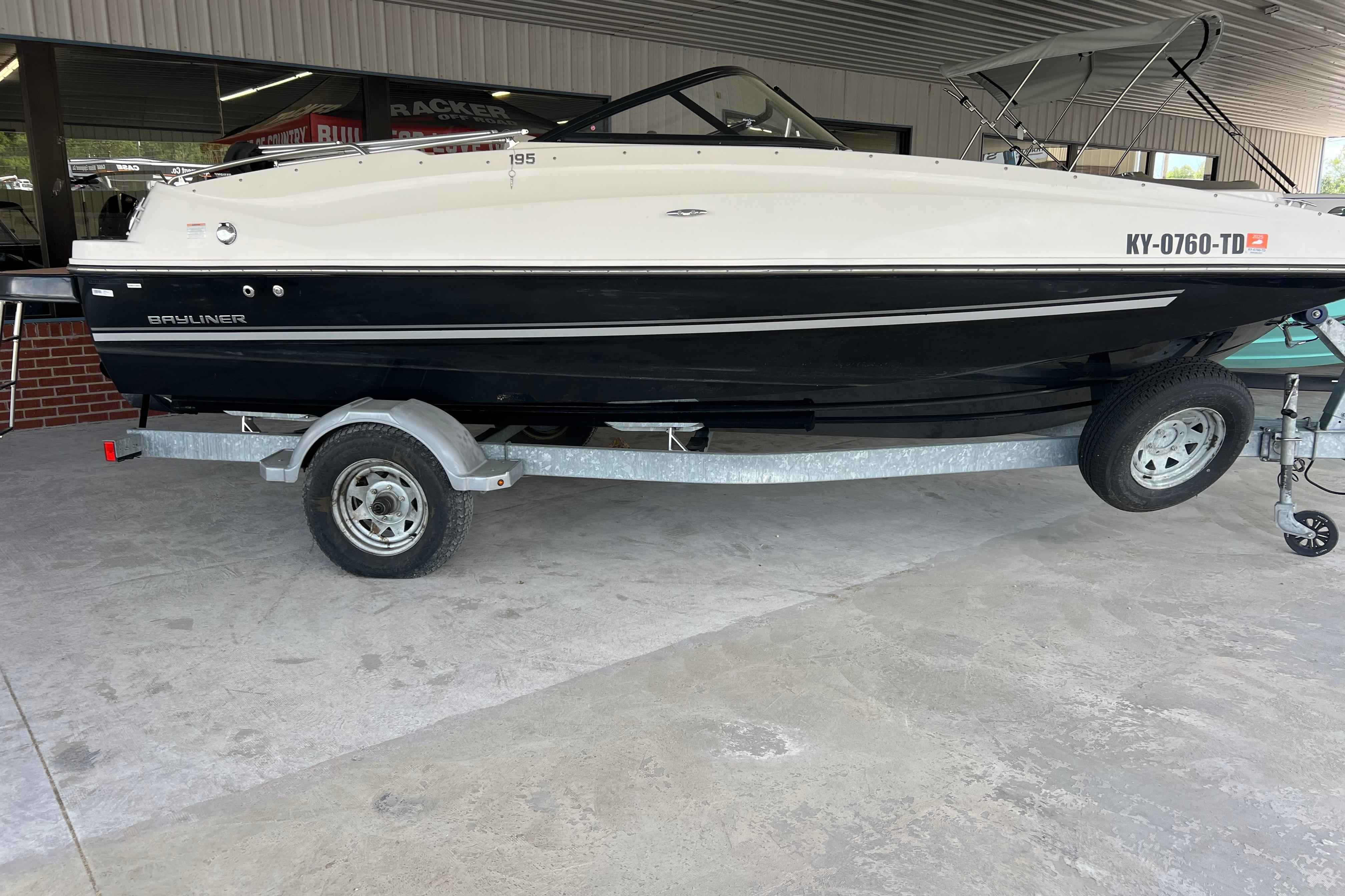 2017 Bayliner 195 Deck Boat on trailer, parked indoors, side view.