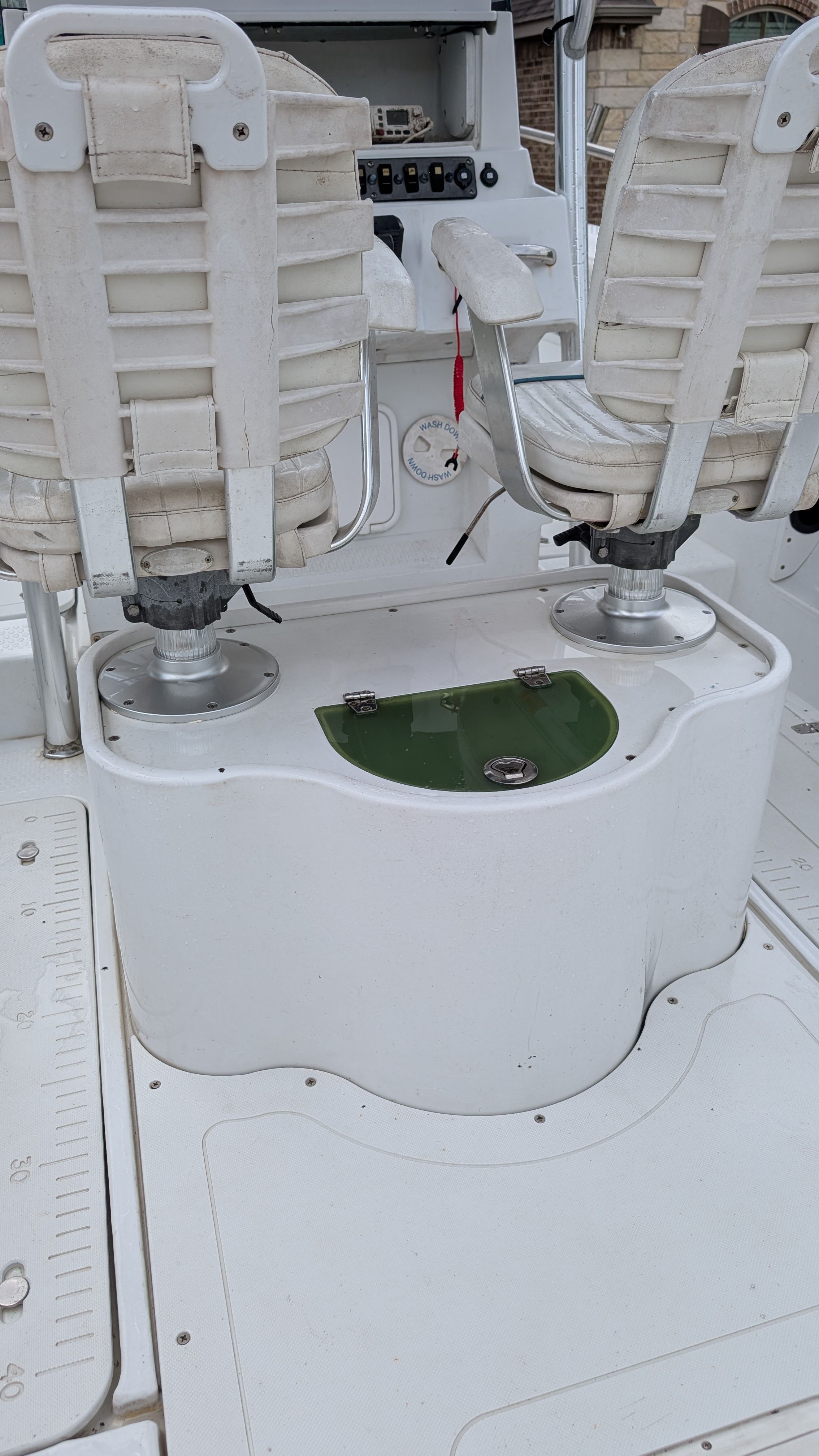 Two white boat seats on a 2007 Triumph 215 CC, with a green compartment below.