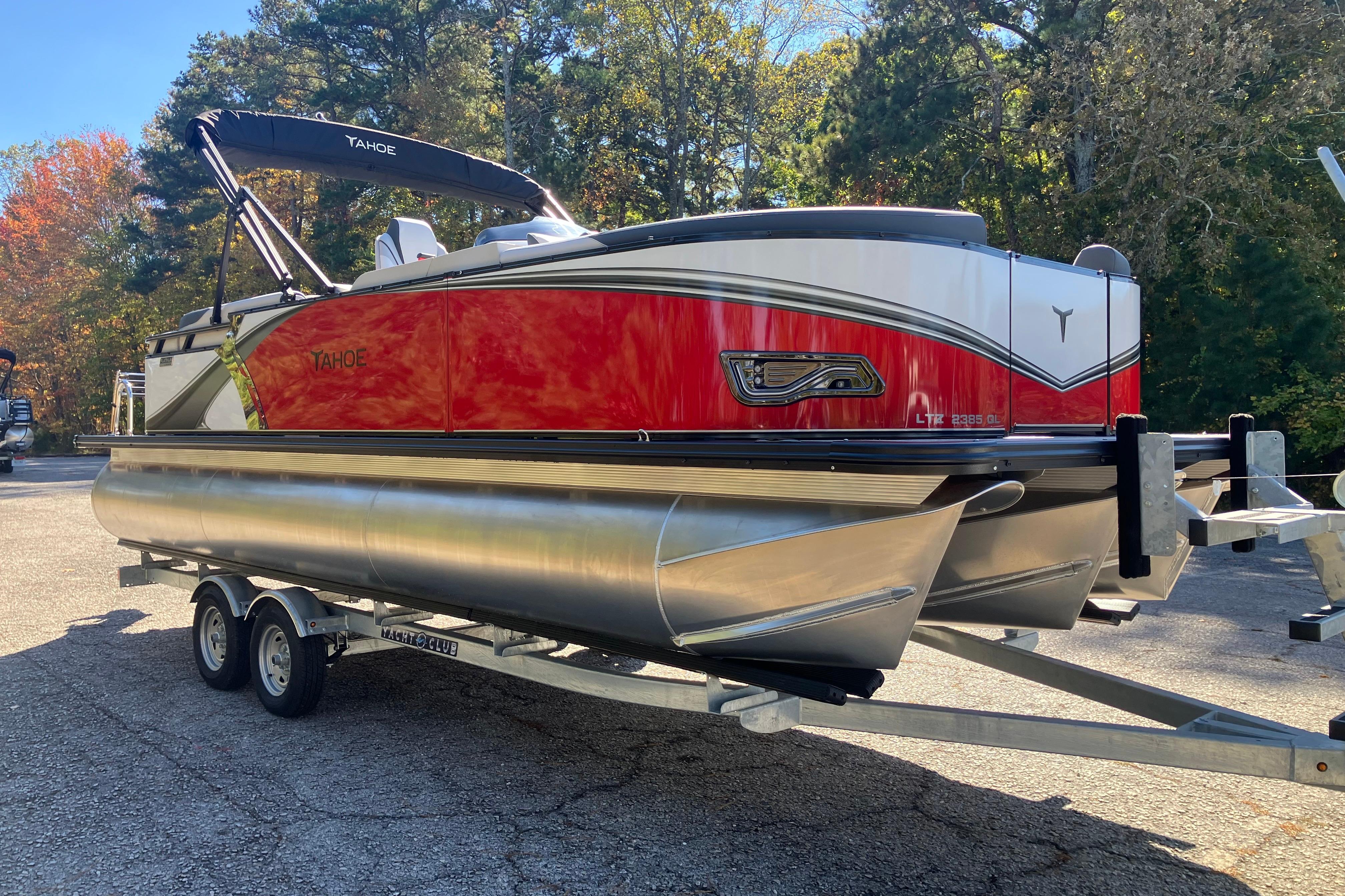 2026 Tahoe Pontoon LTZ Quad Lounger on trailer, parked outdoors with trees in background.