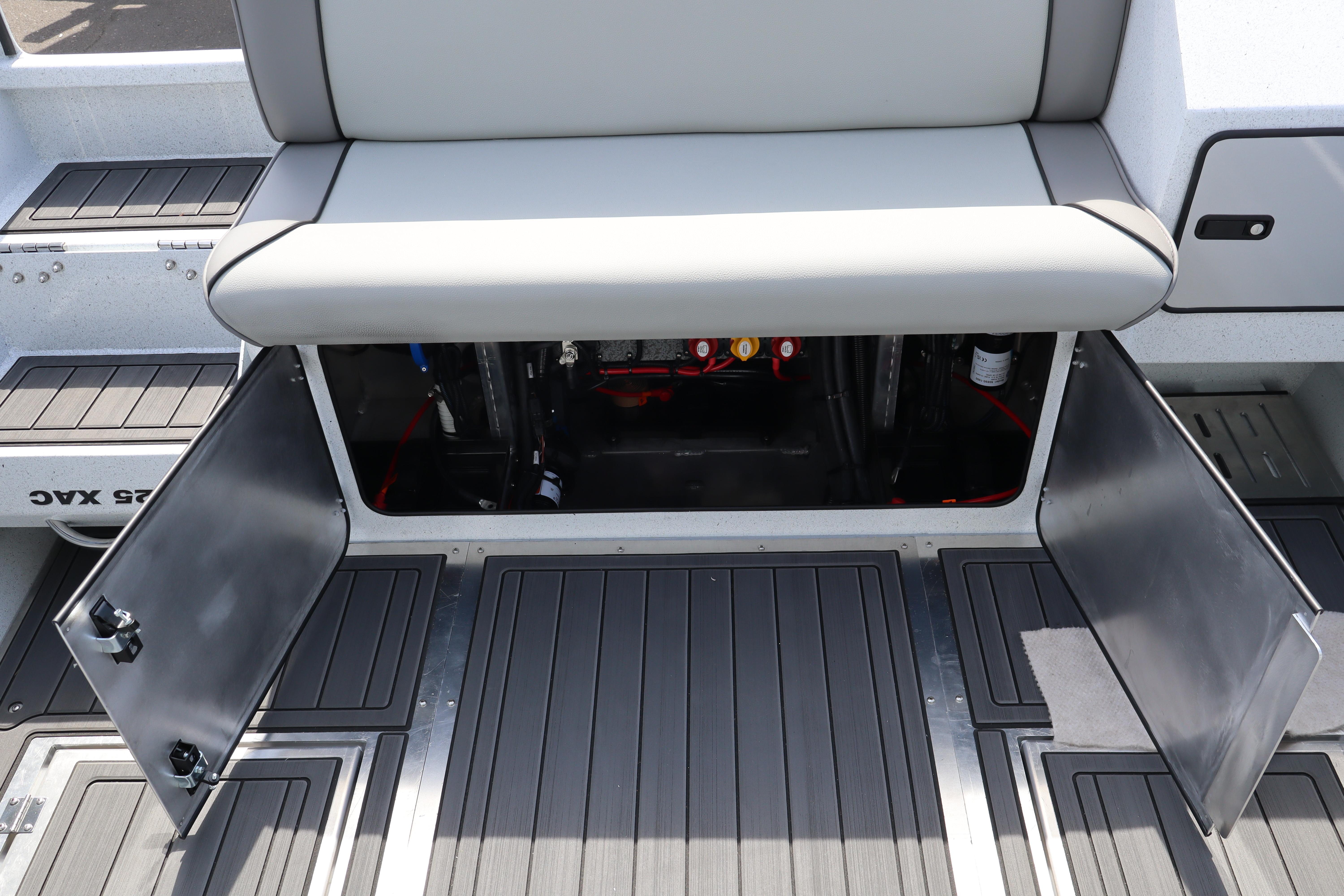 Open storage compartment on 2026 KingFisher 25 XAC boat with gray seating and flooring.
