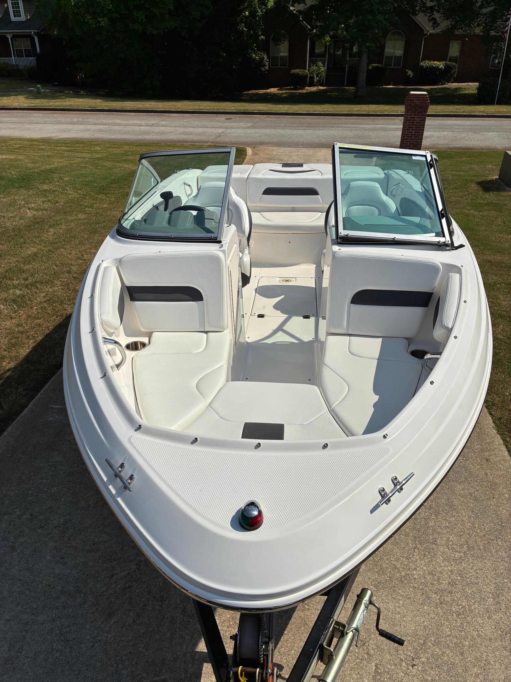A 2012 Chaparral 19 H2O Sport boat is on a trailer in a driveway.