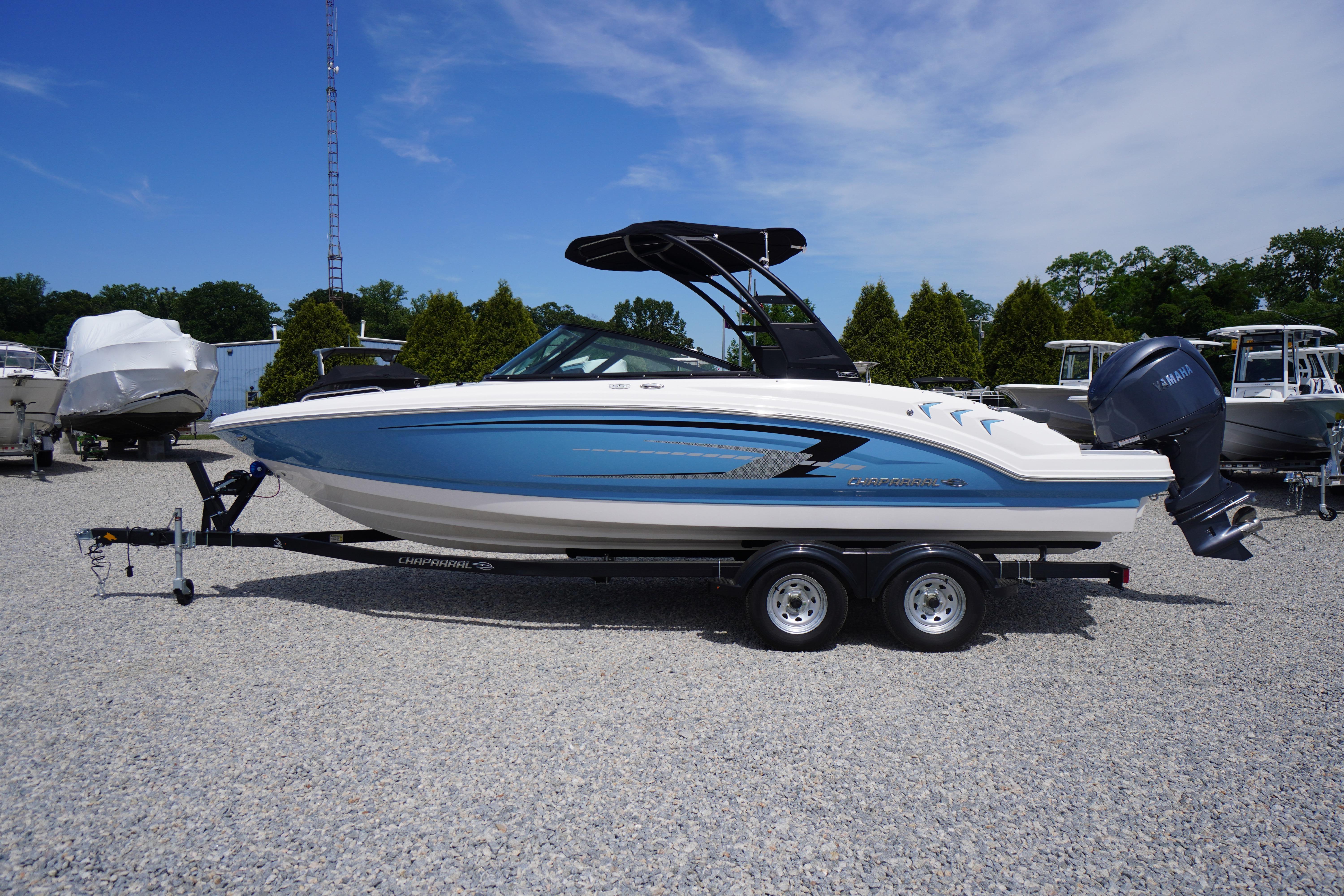 2026 Chaparral 23 SSi OB boat on trailer, blue and white design, outdoor display.