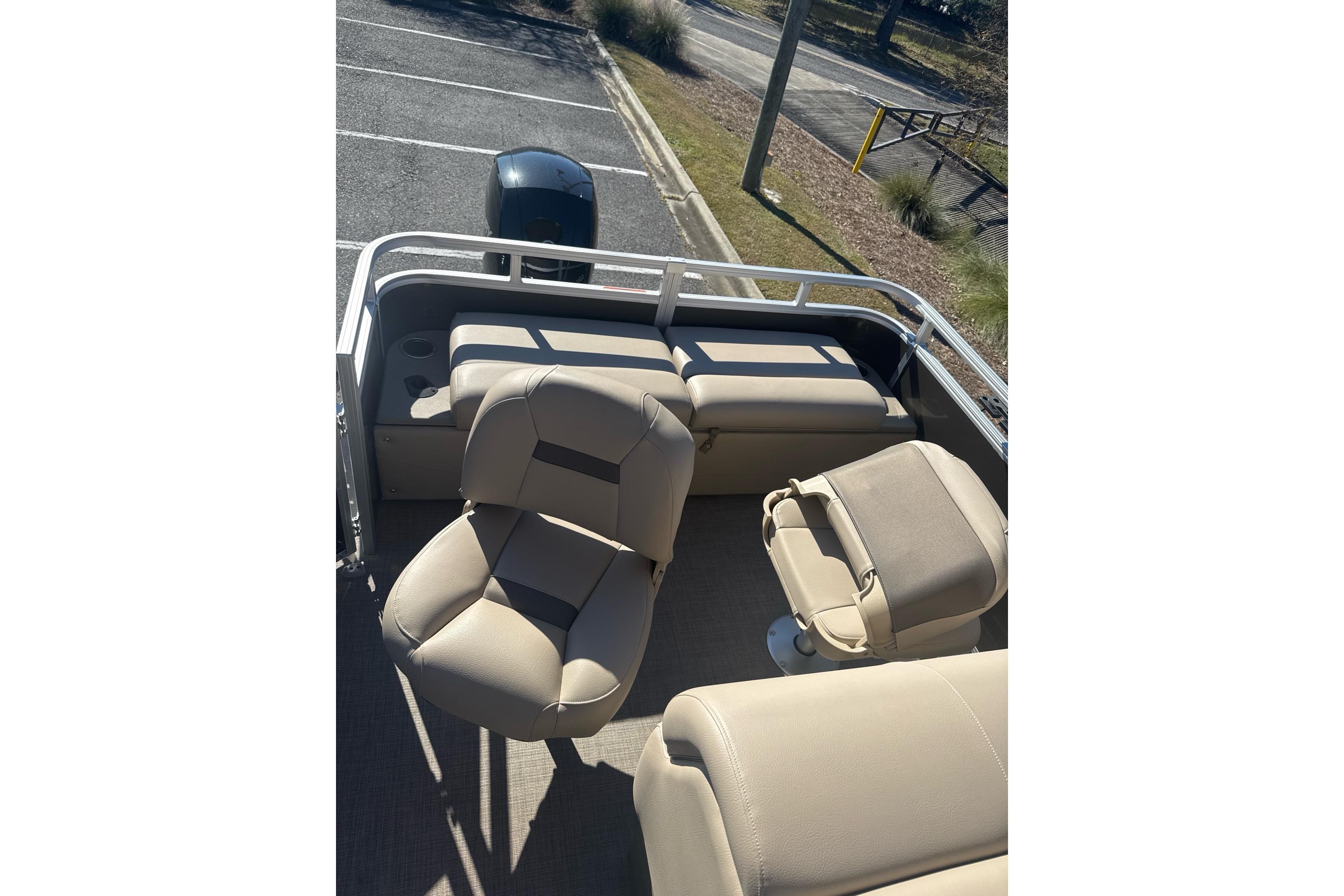 2025 Sun Tracker SportFish 22 DLX interior with beige seating and outdoor view.